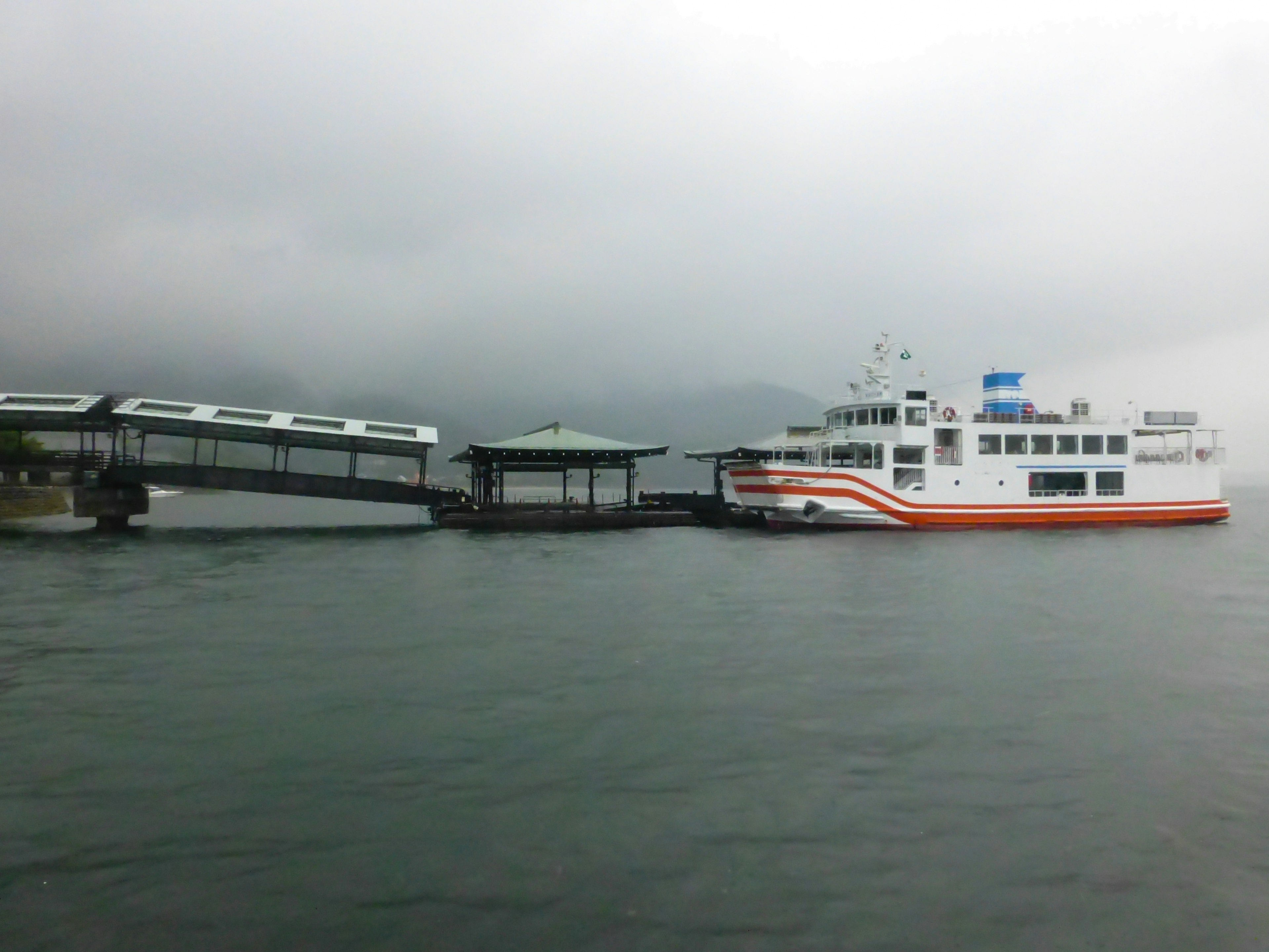 A white ferry at a dock under a cloudy sky