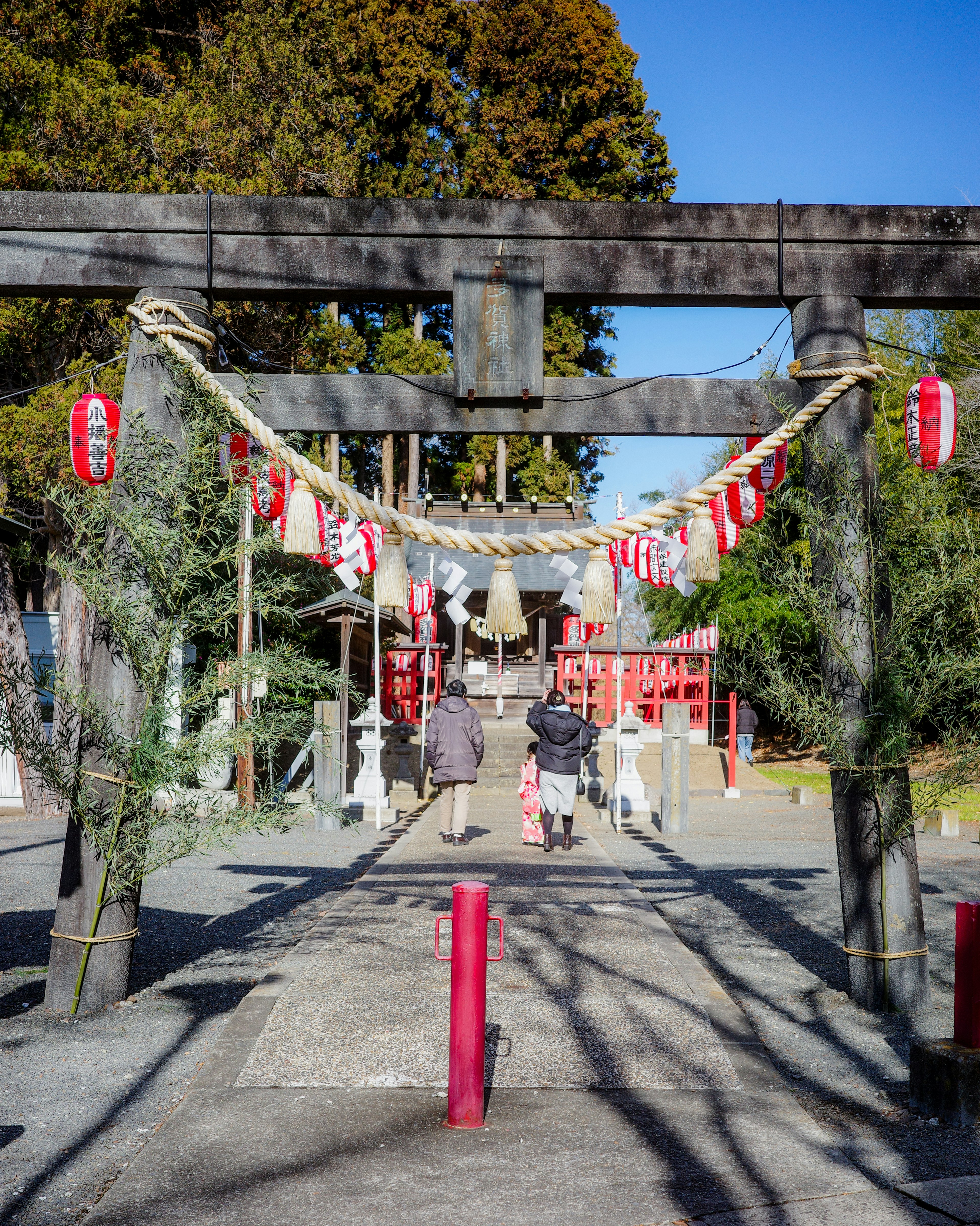 神社の鳥居と提灯が飾られた参道を歩く人々の風景