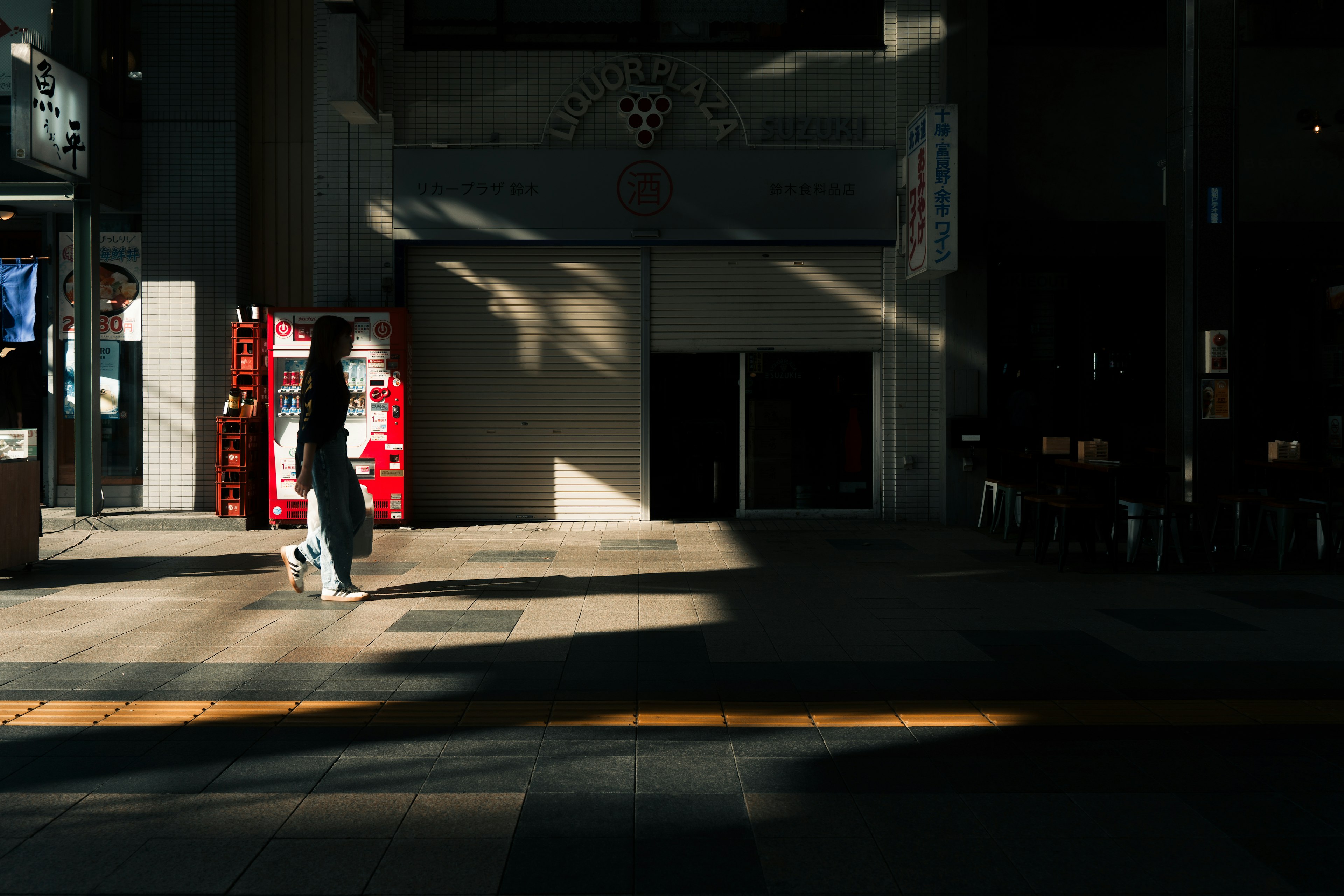 Una persona che cammina in una strada di città con un bel contrasto di ombre e luce