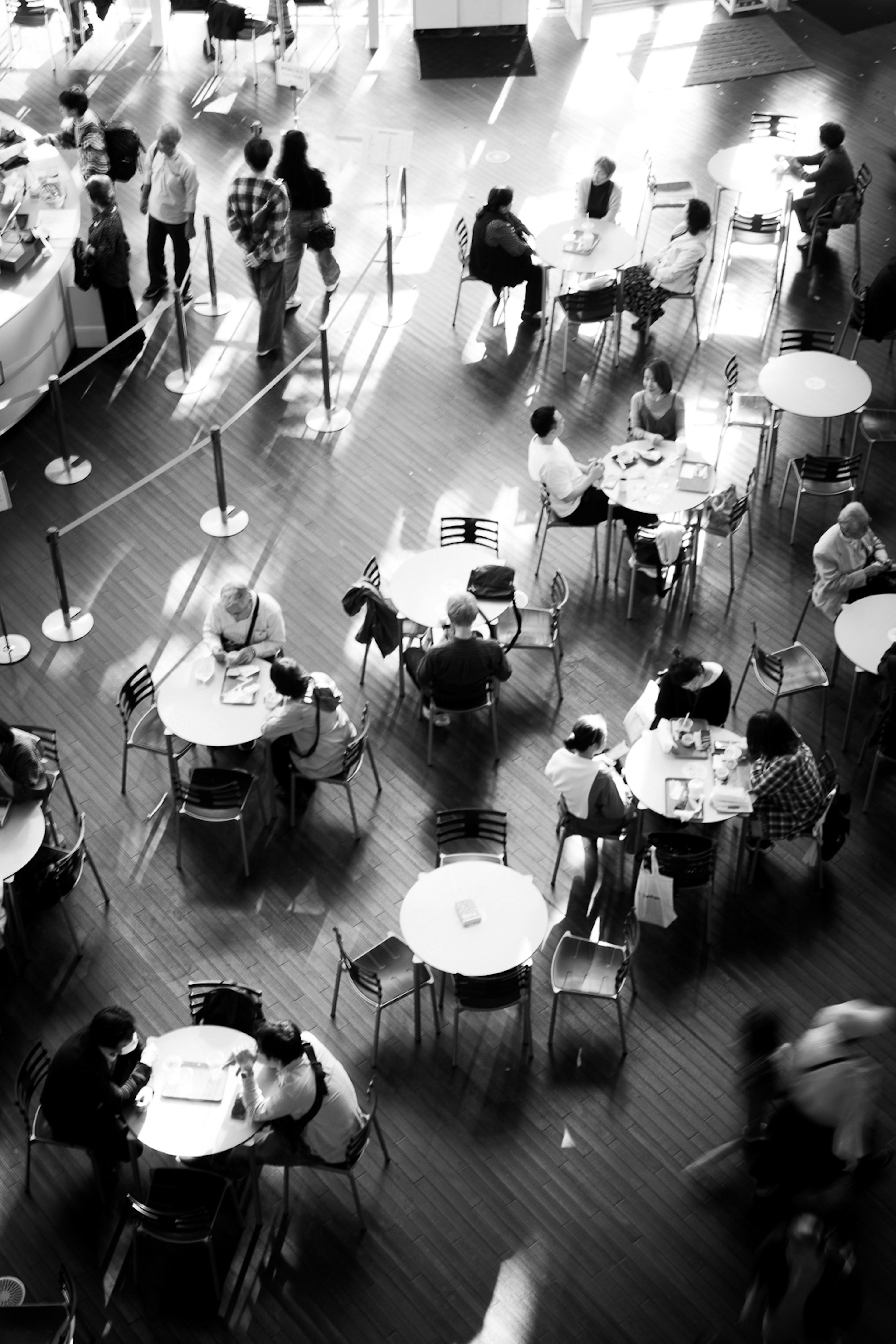 Escena de café en blanco y negro con personas alrededor de las mesas