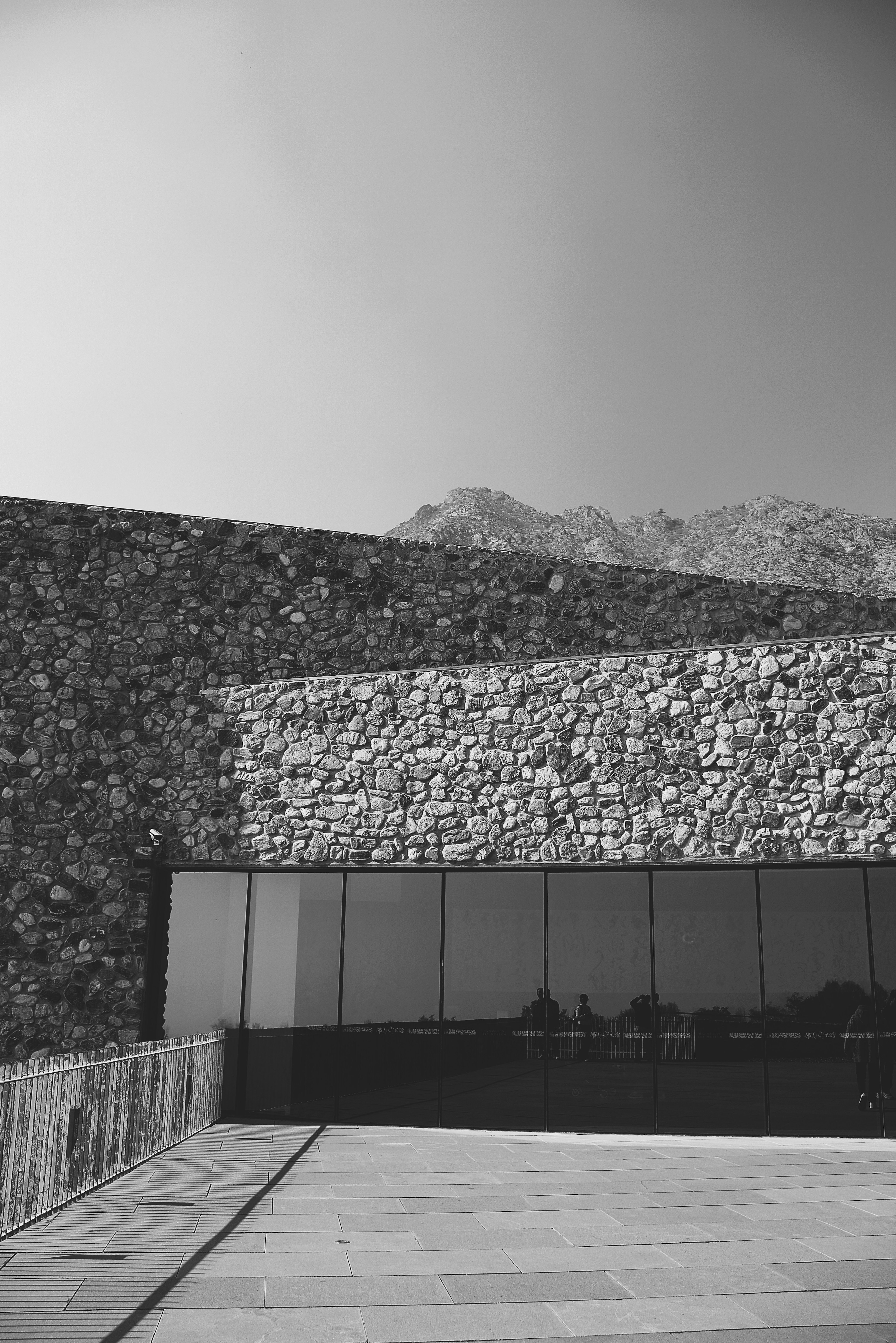 Exterior arquitectónico en blanco y negro con pared de piedra y fachada de vidrio