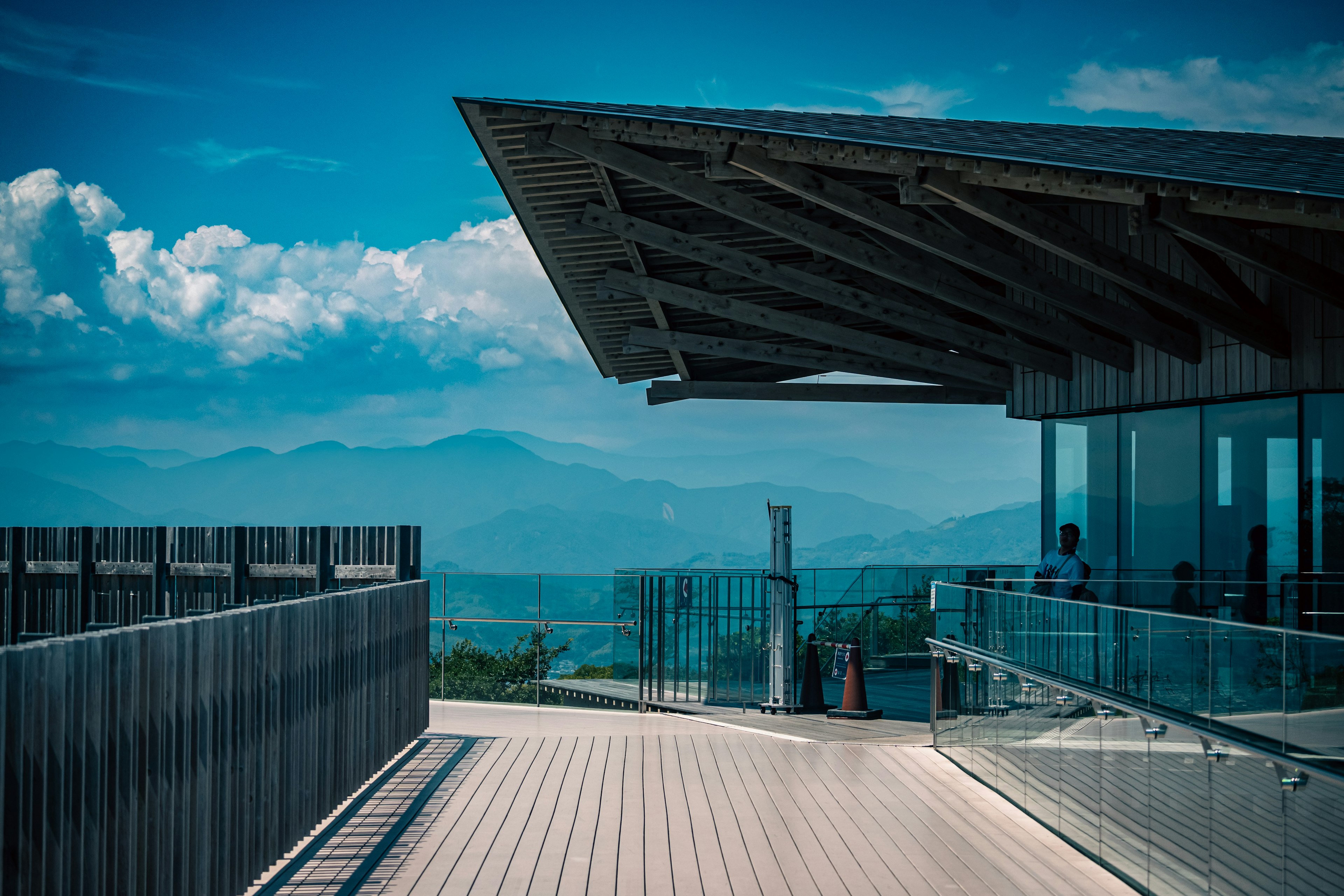 Terrazza moderna con tetto in legno che si affaccia su montagne e cielo blu