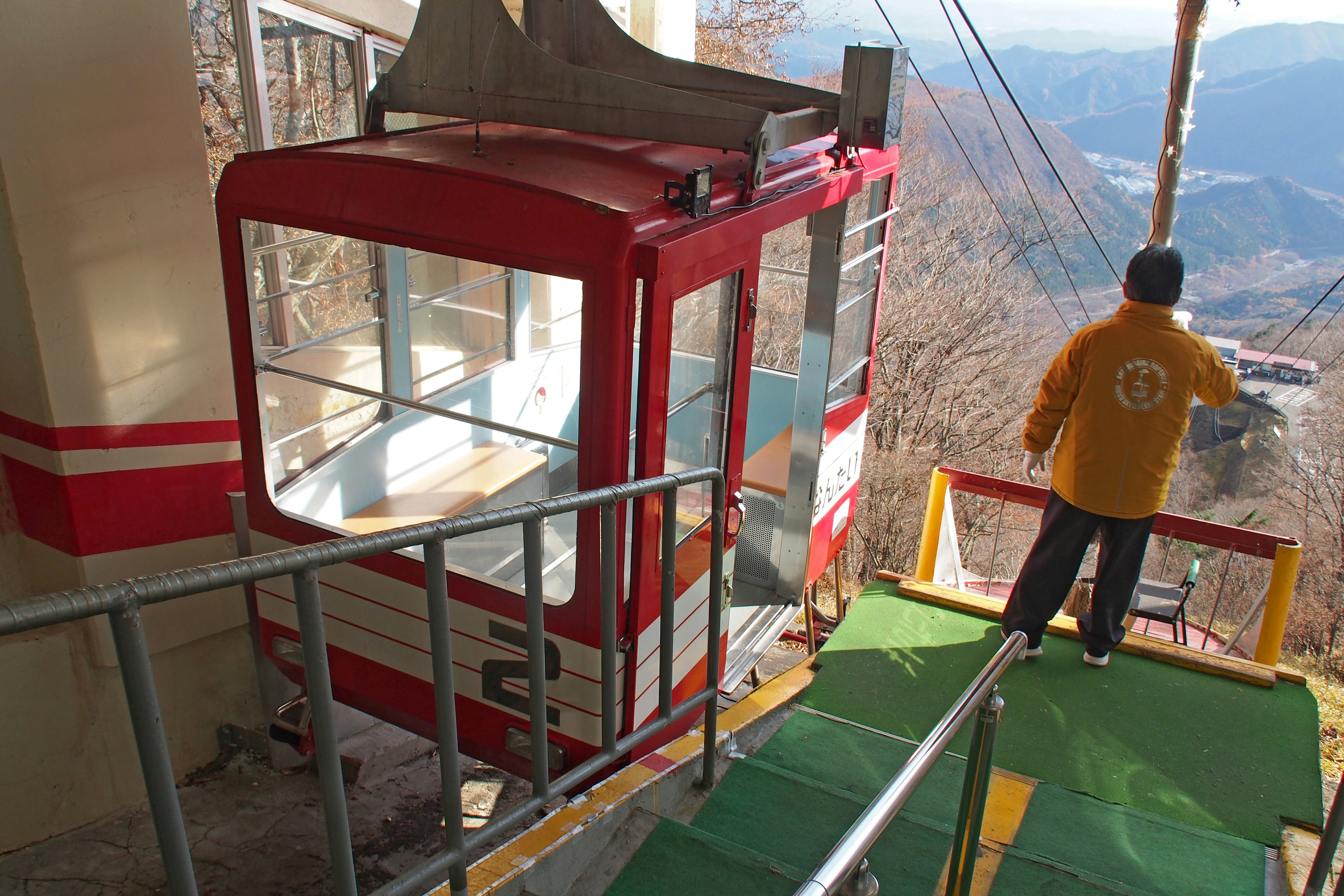 Rote Seilbahn an der Station mit einer Person, die sich zum Einsteigen bereit macht