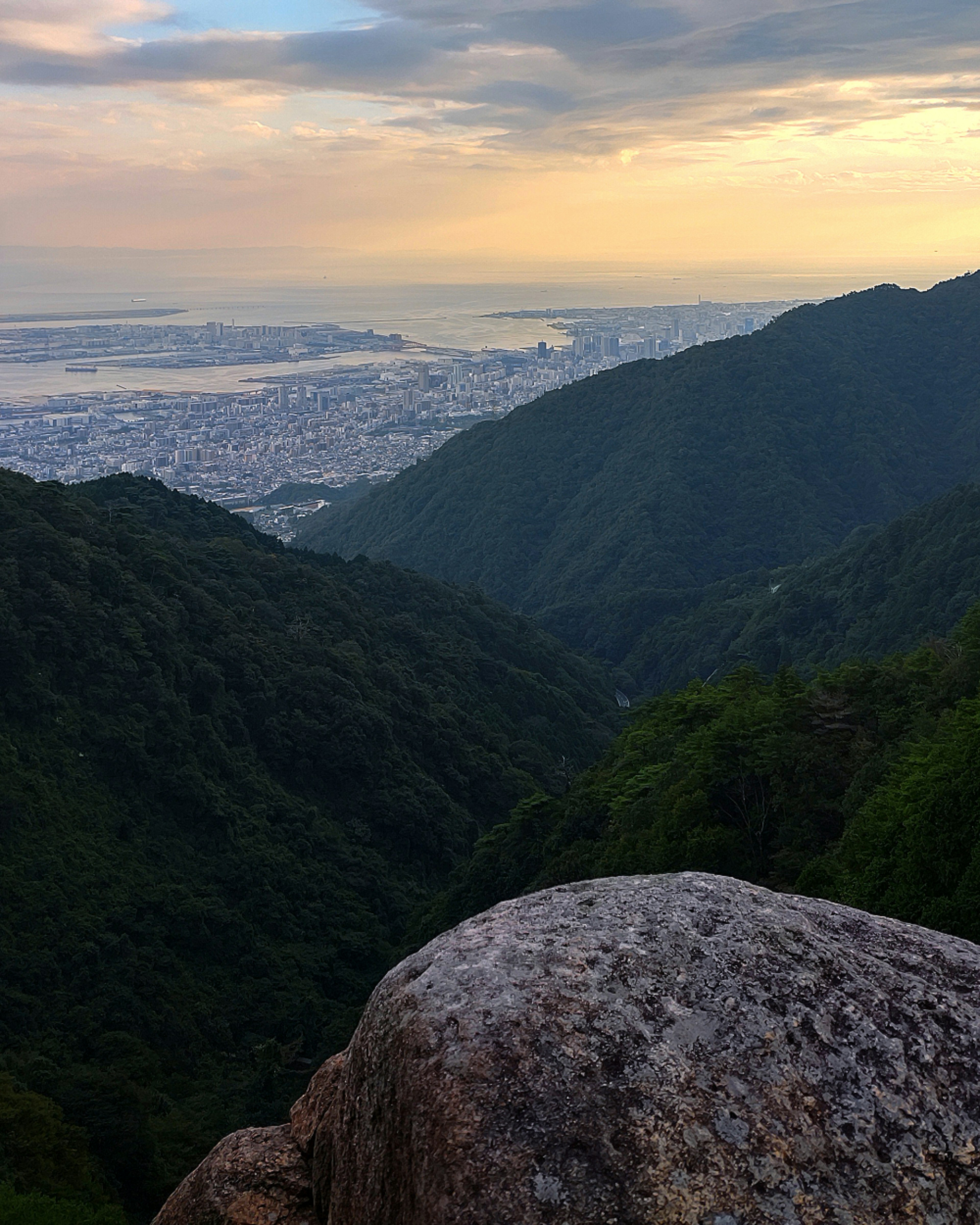 View of a city from a mountain valley with sunset sky