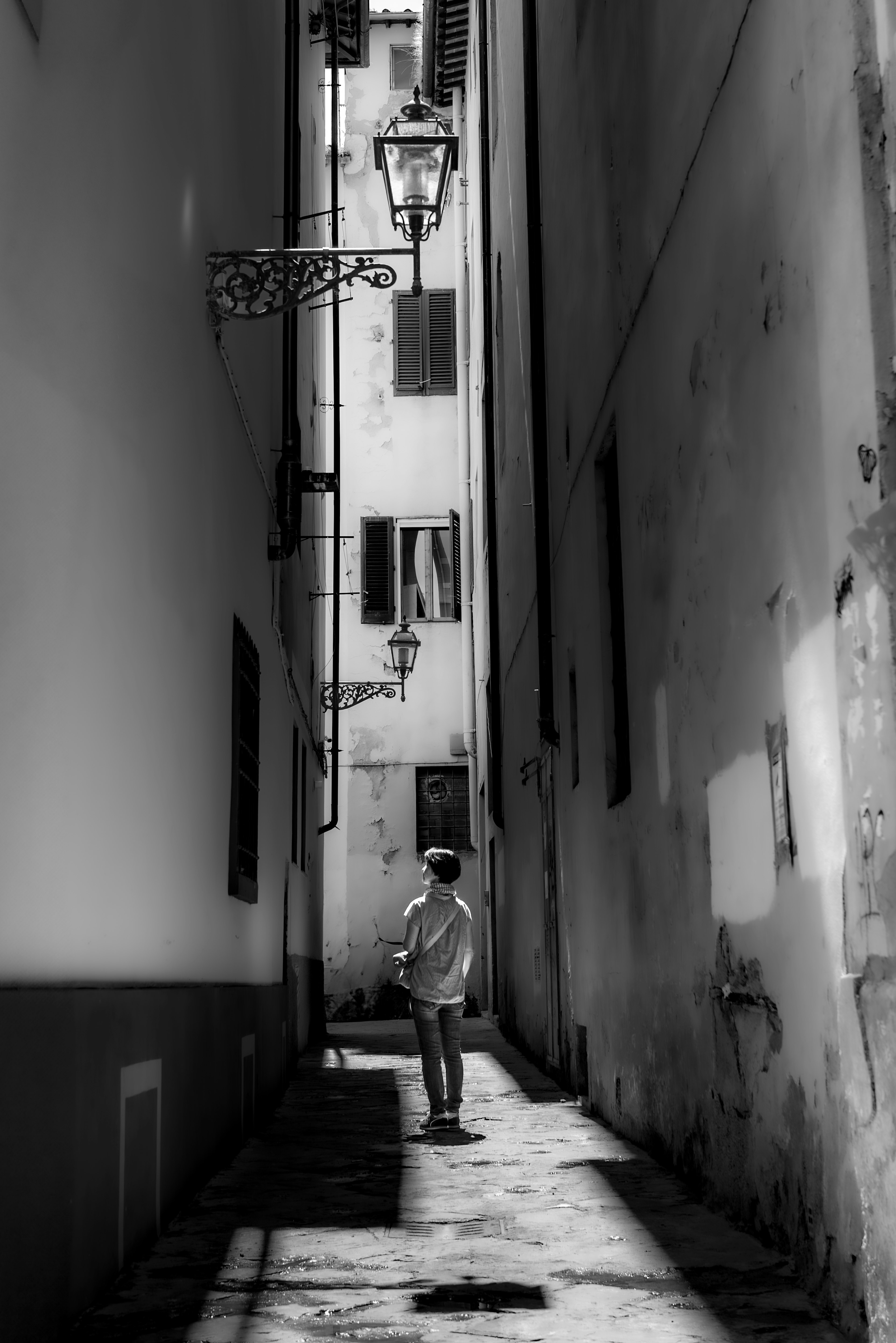 狭い路地を歩く人のモノクロ写真