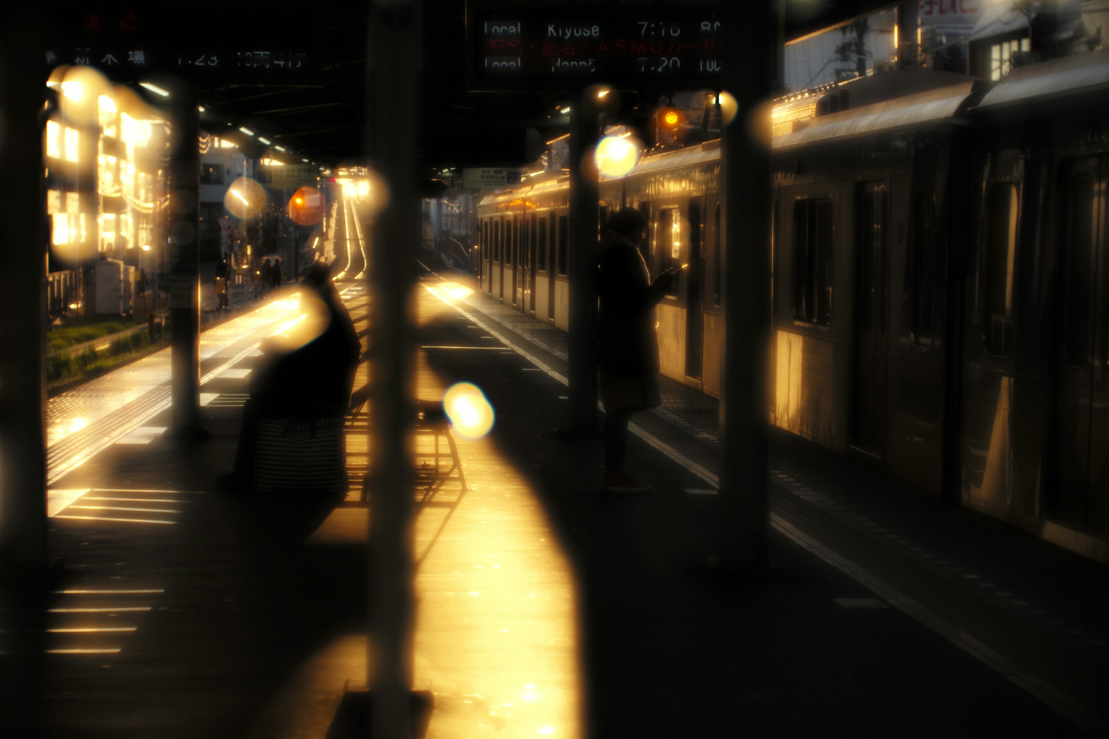 Figuras borrosas en una plataforma de tren de noche con vagones iluminados