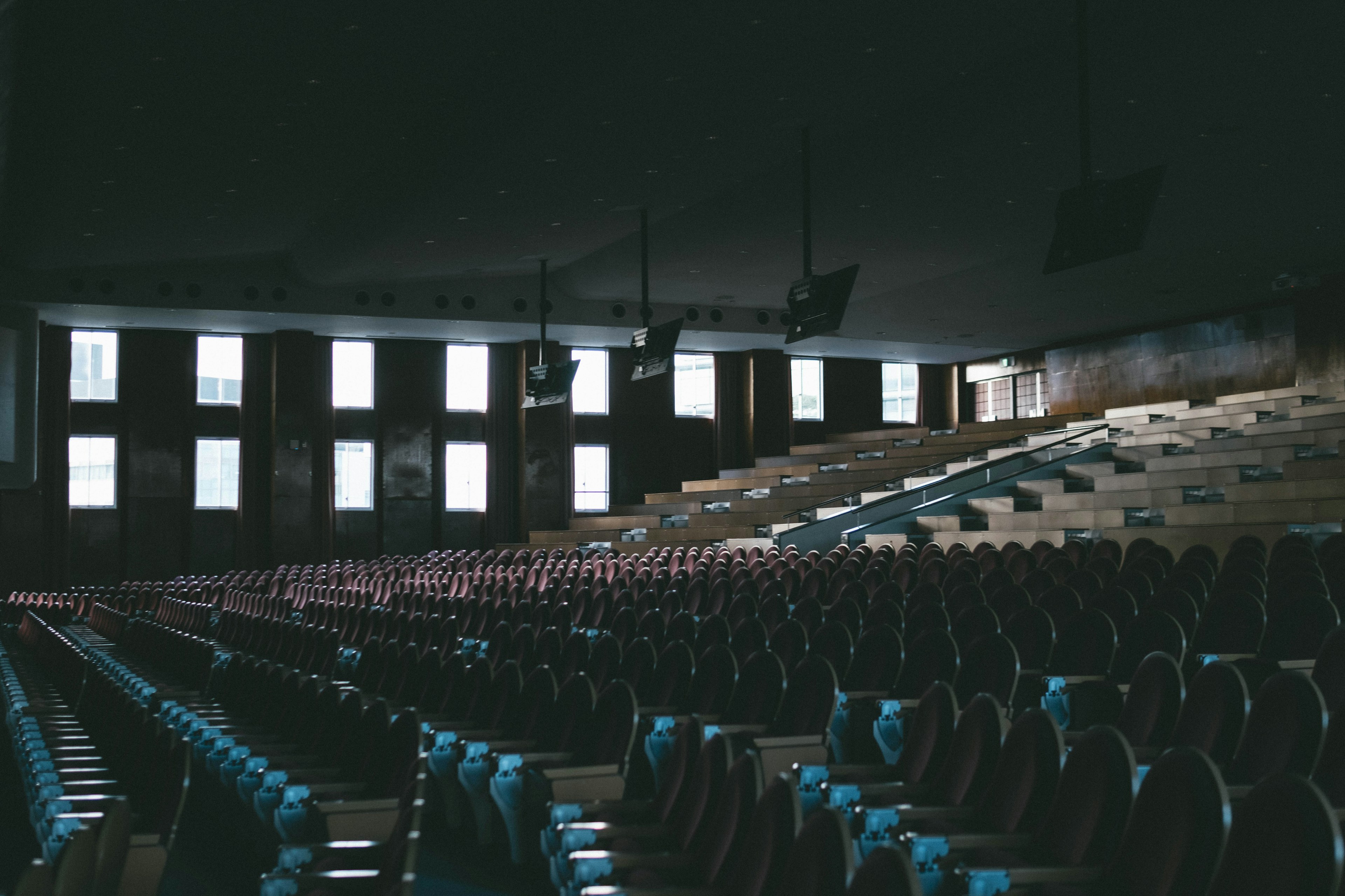 Intérieur d'un stade sombre avec des rangées de sièges bleus et rouges et de grandes fenêtres