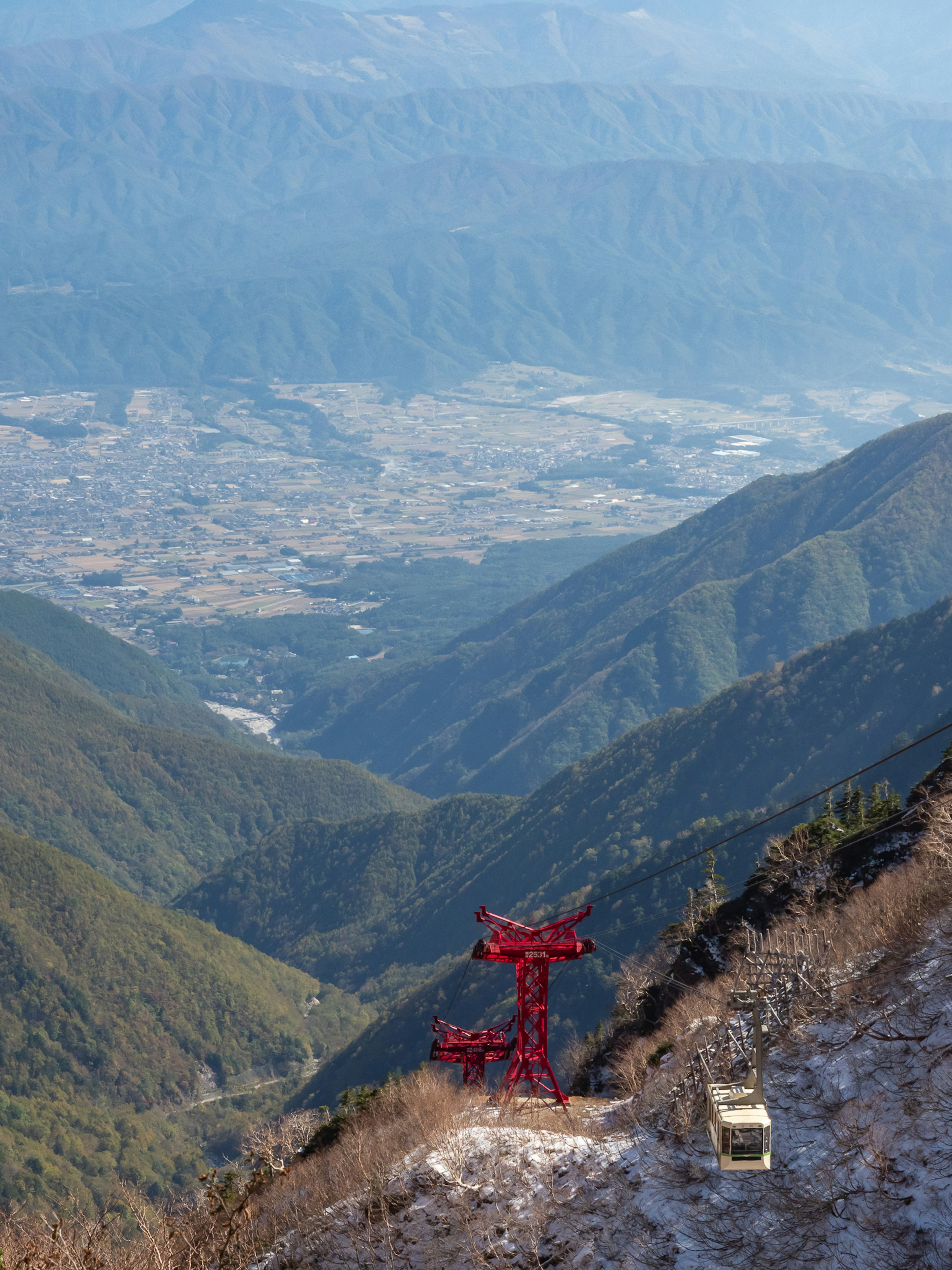 Red cable car on a mountain slope with a distant valley view