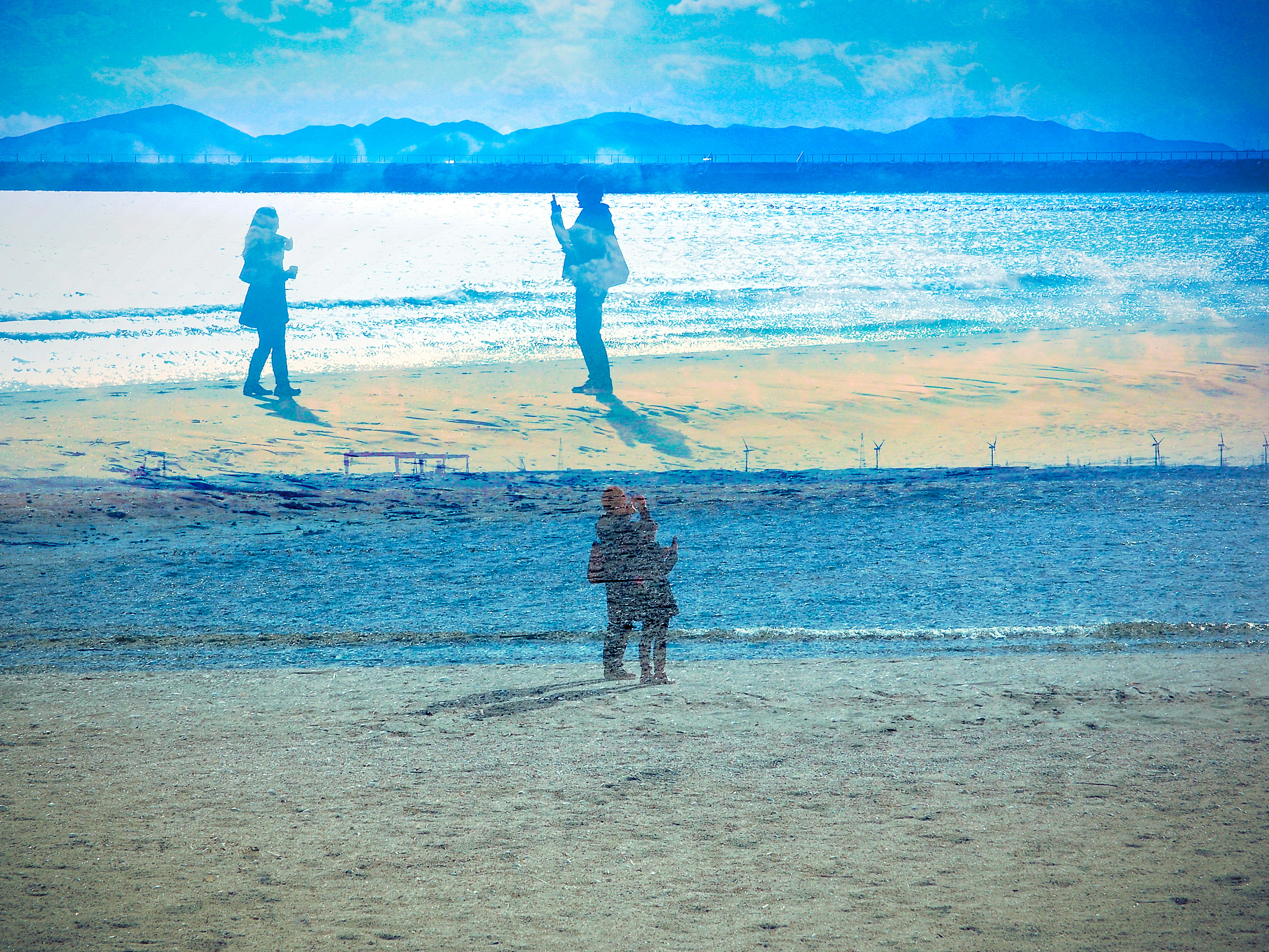 Una vista escénica de dos personas de pie en la playa bajo un cielo azul