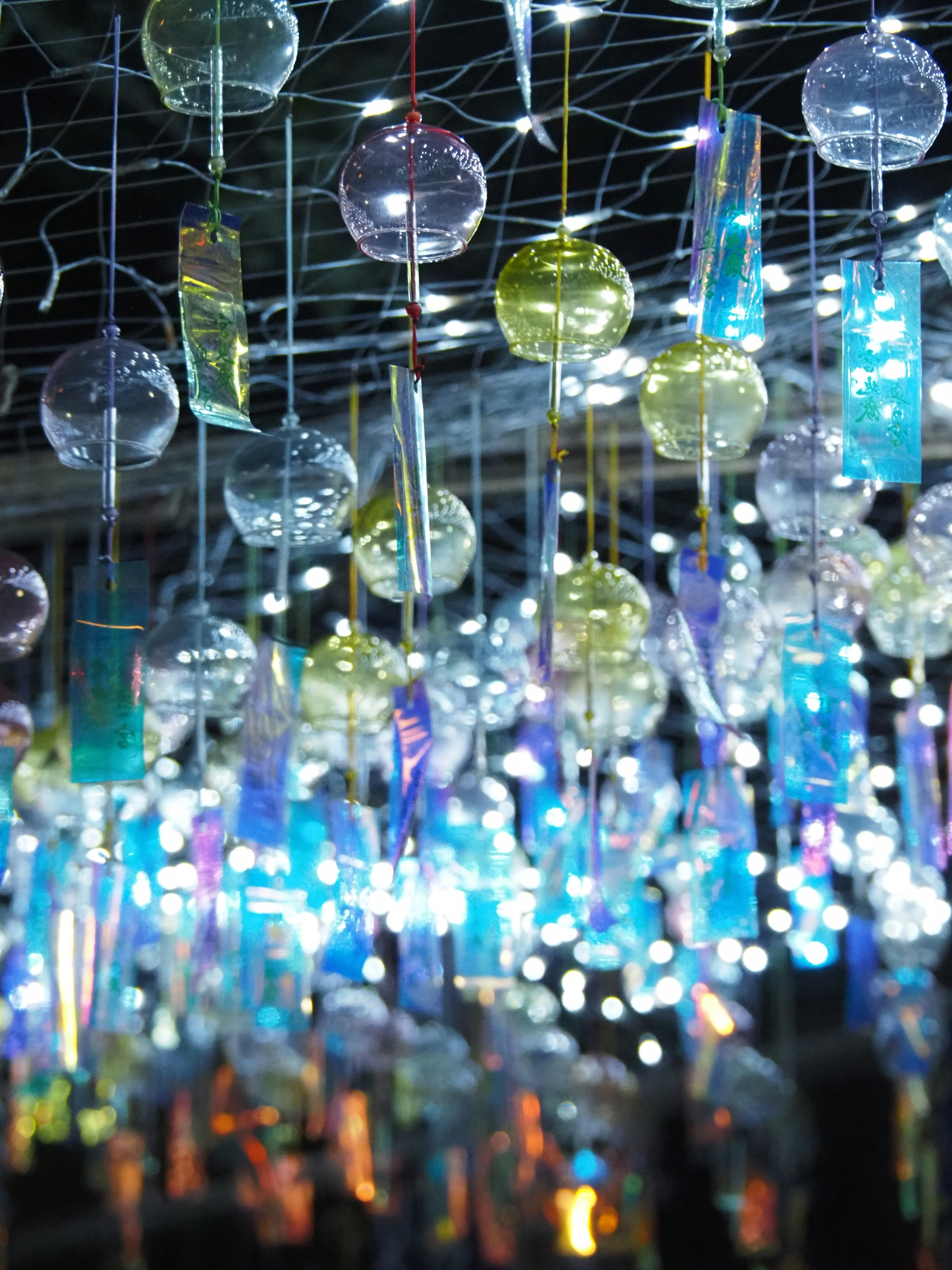 A whimsical display of colorful glass wind chimes hanging from a ceiling