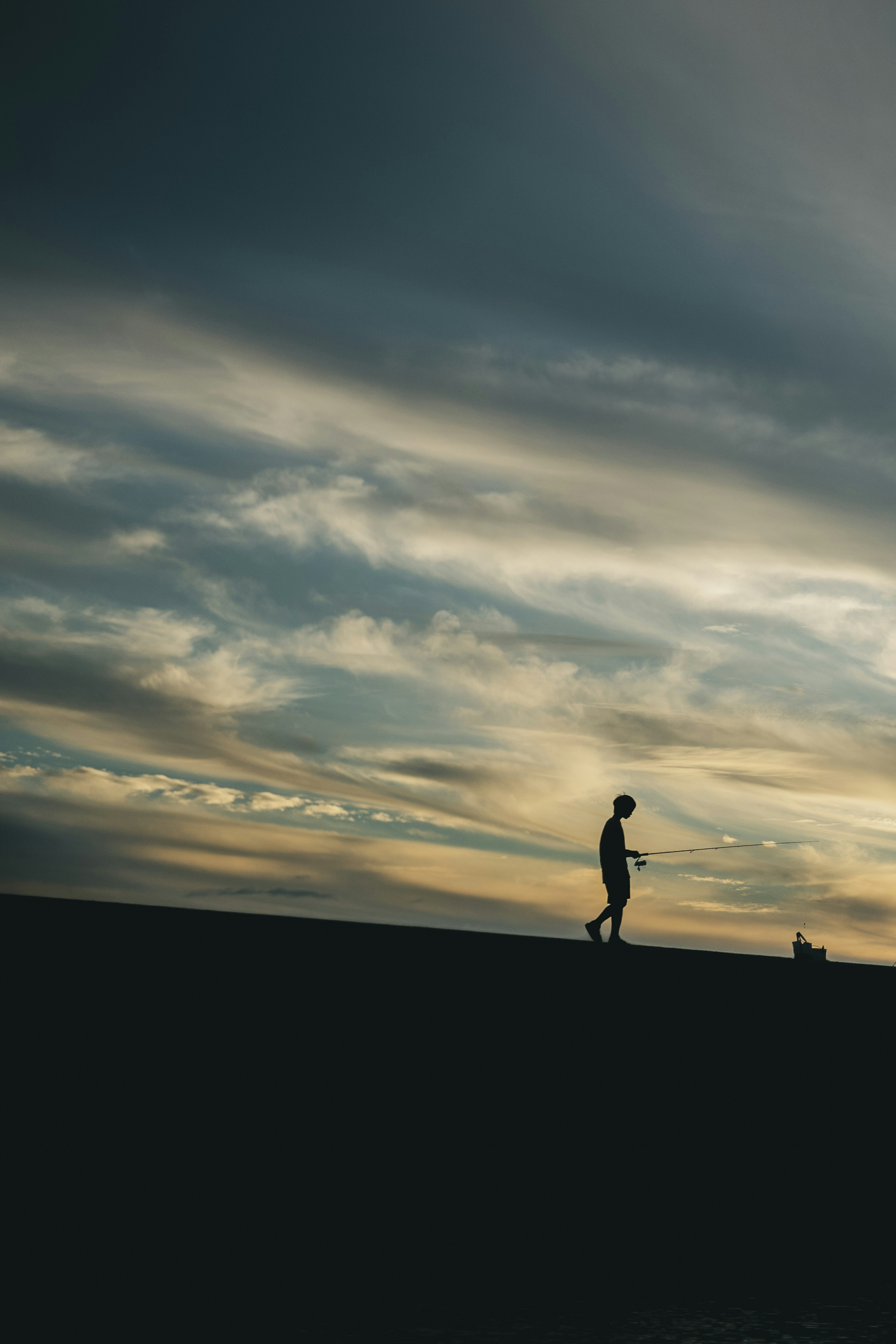 Silhouette of a person walking against a dramatic sky with clouds