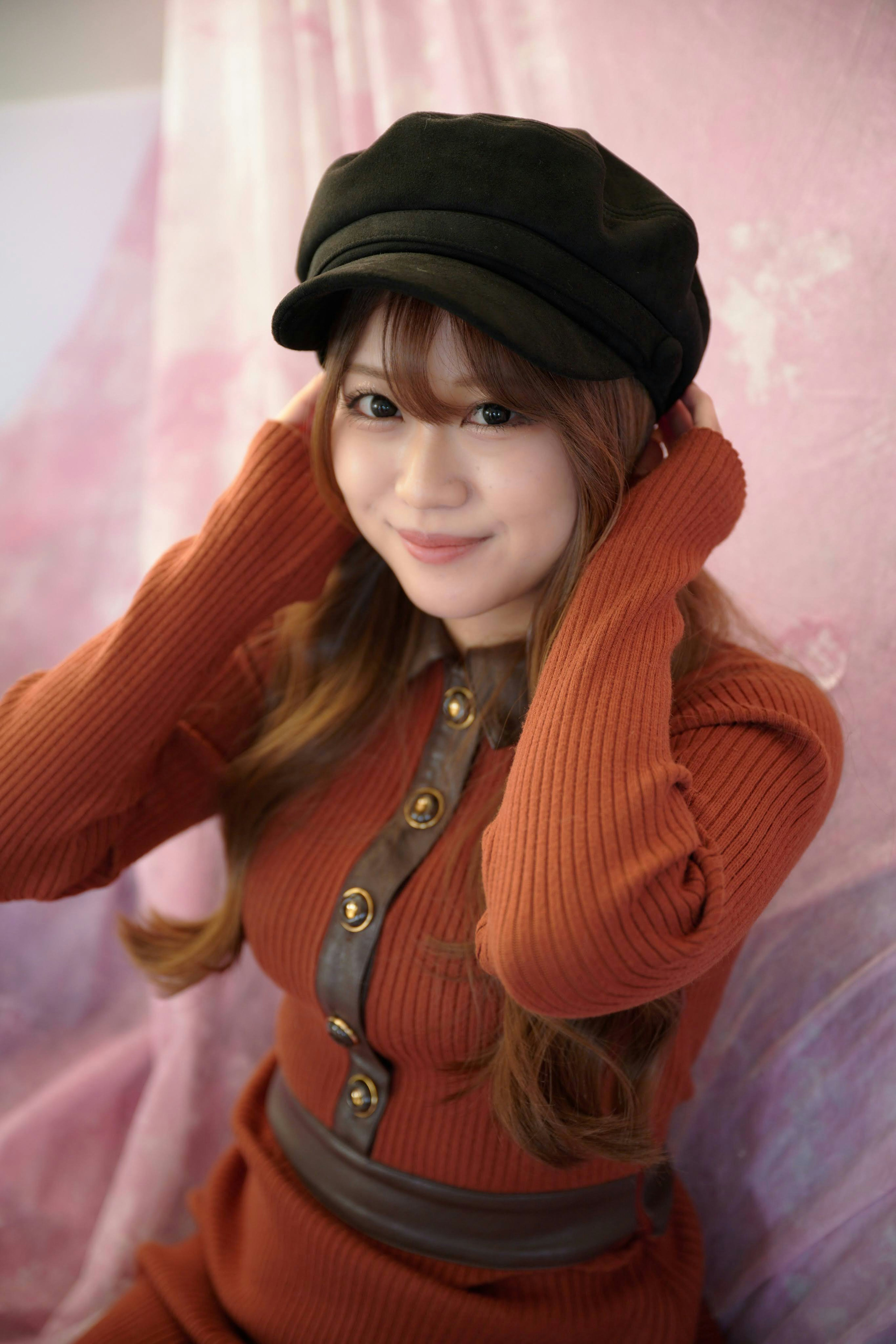 Woman smiling in an orange outfit and black hat