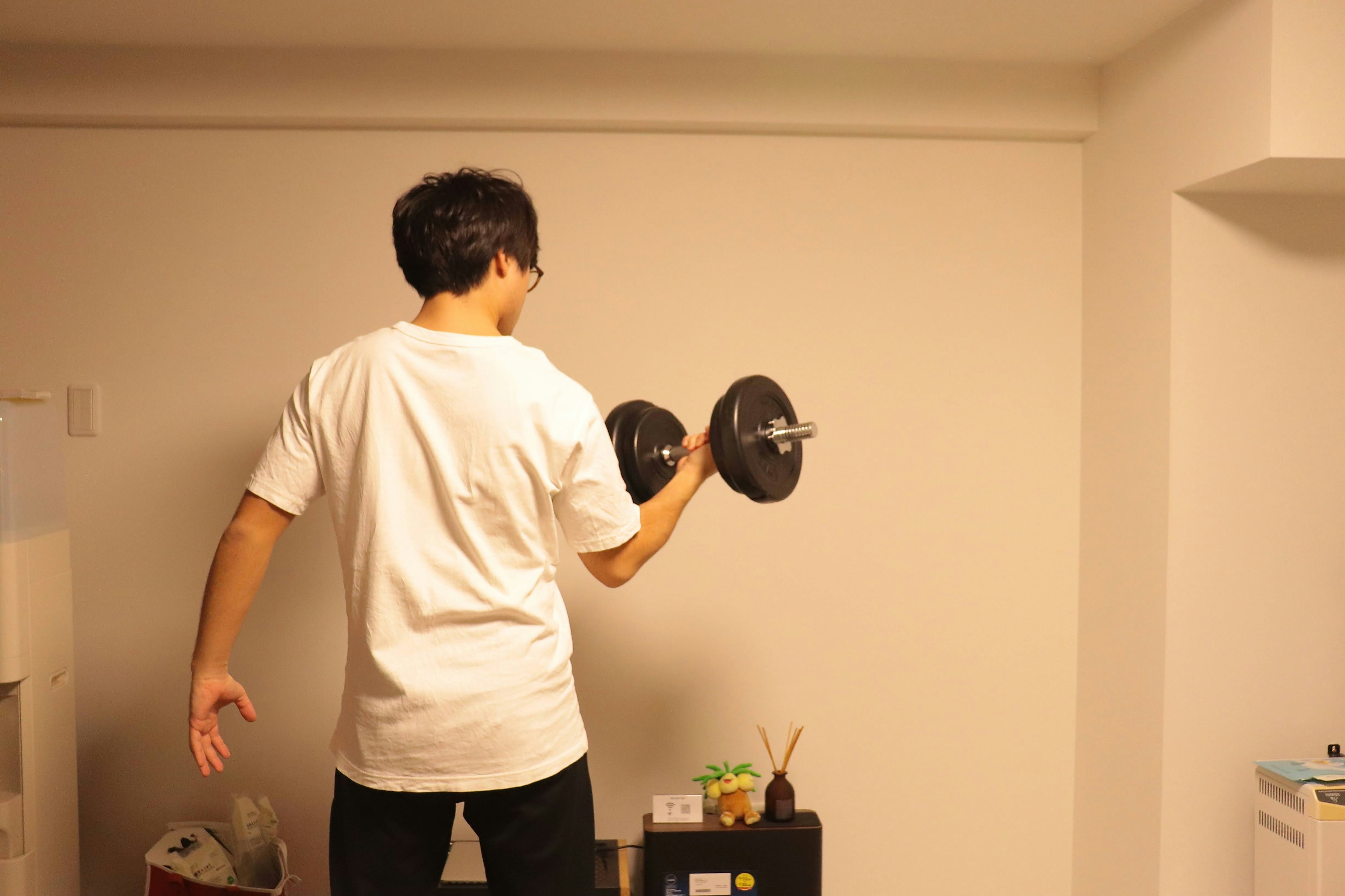 Hombre haciendo ejercicio con mancuernas de espaldas a una pared