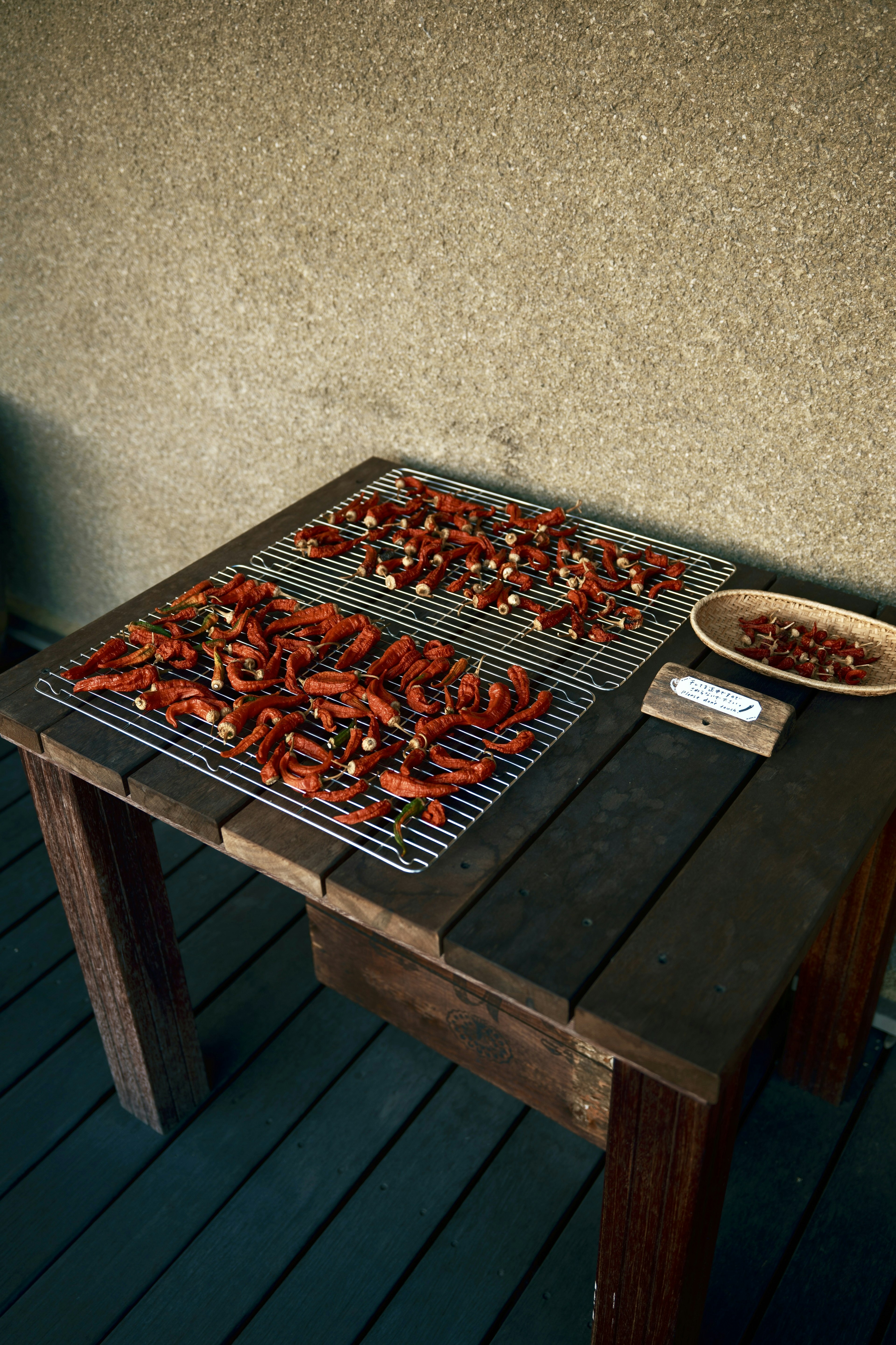 Dried chili peppers on a grill and nuts in a bowl on a table