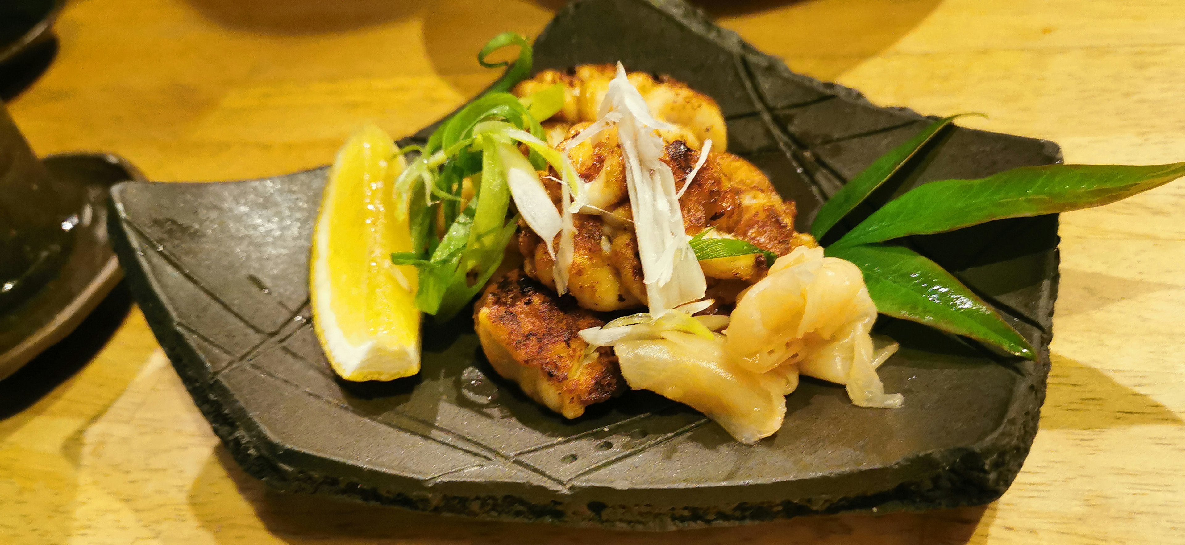 Grilled fish dish garnished with lemon and green onions