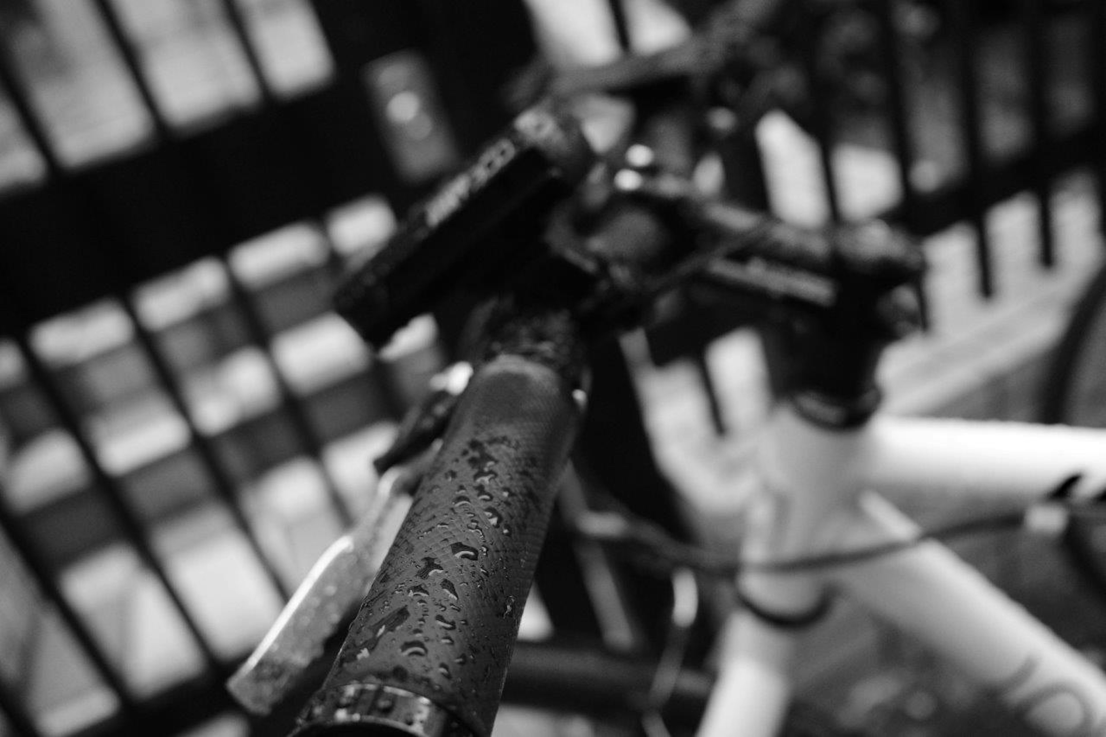 Gros plan d'un guidon et d'un cadre de vélo couverts de gouttes de pluie en noir et blanc