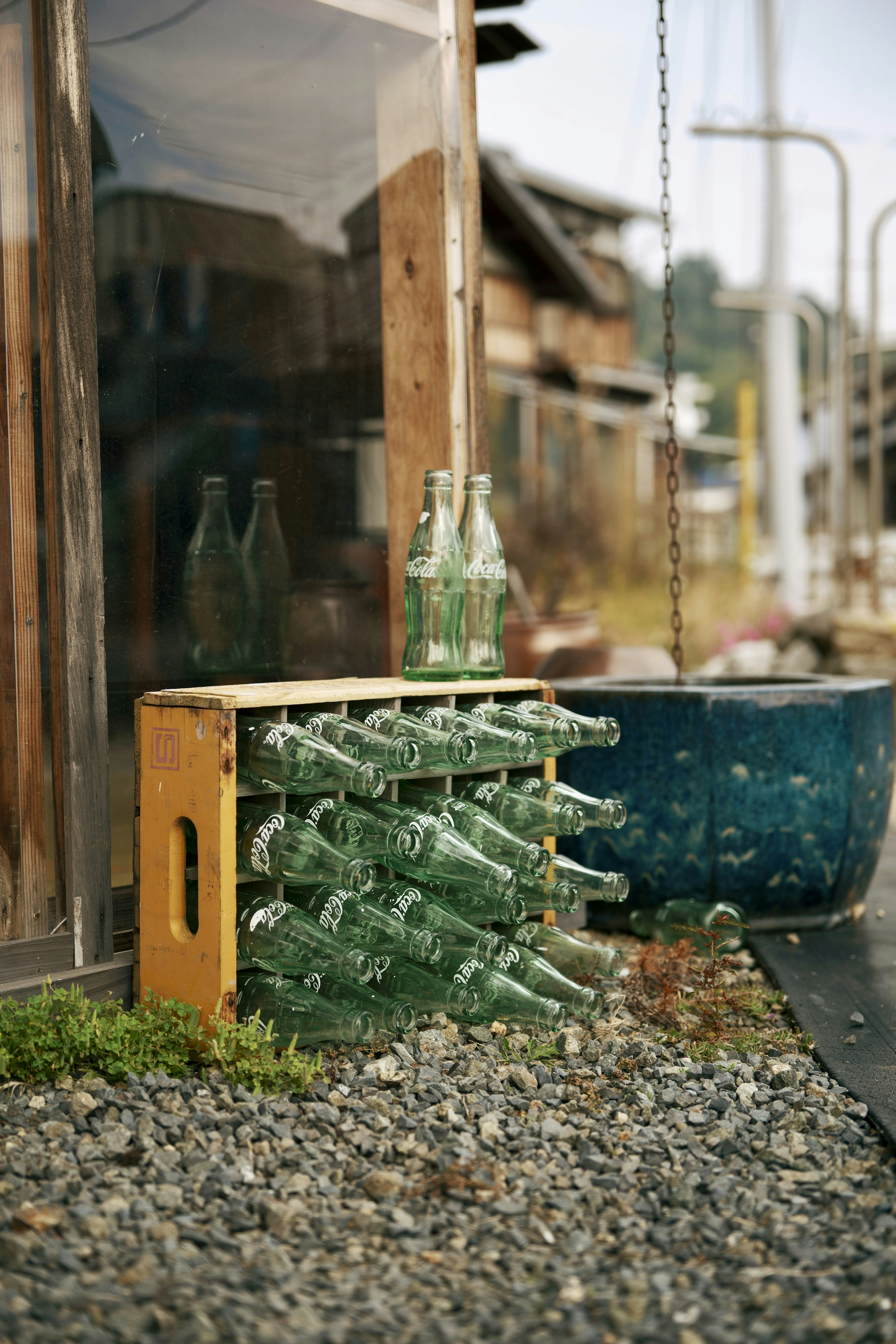 古い瓶が並ぶ木製の箱と小石の床のある風景