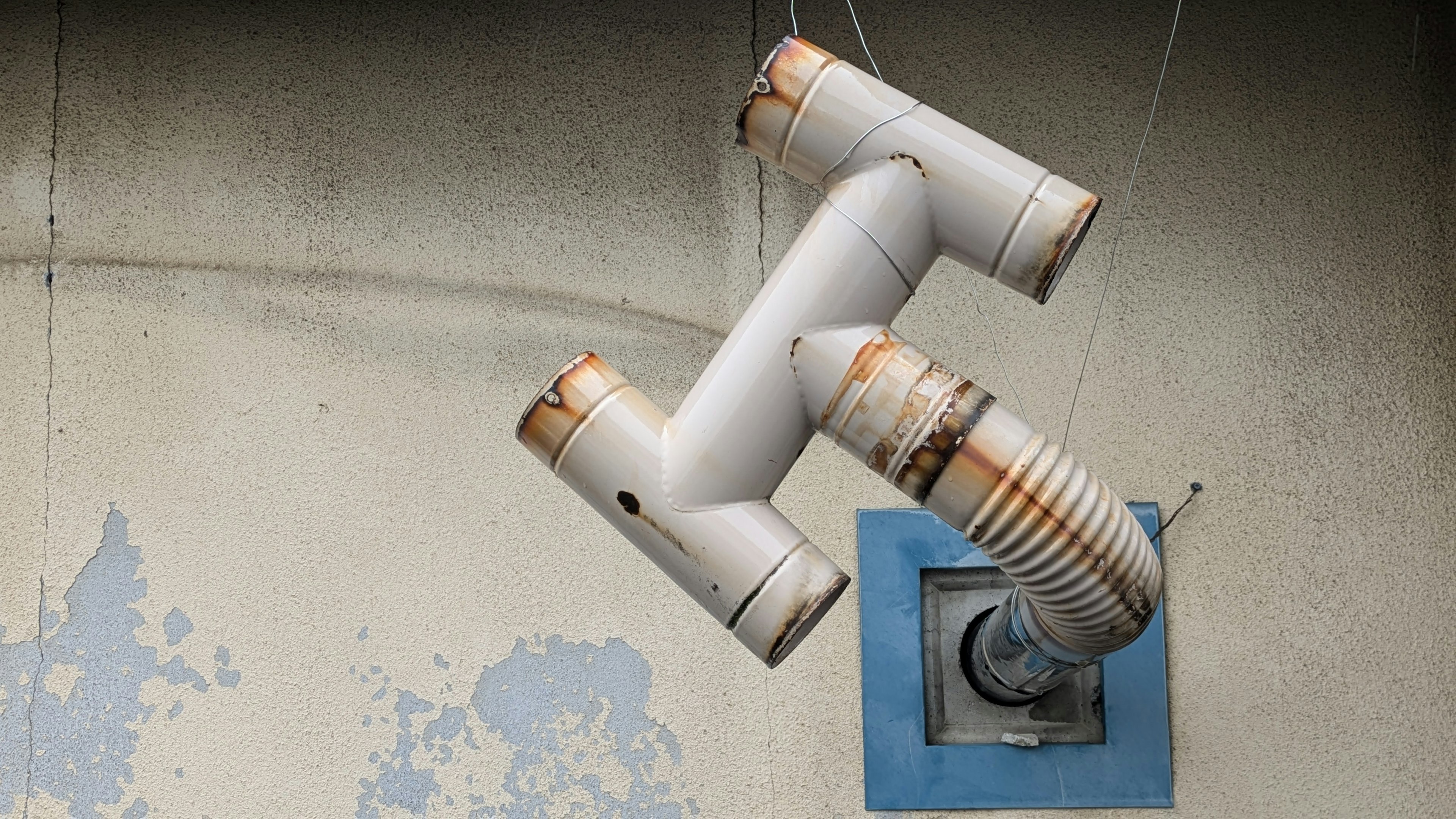 Image de tuyaux blancs et d'une sortie de ventilation sur un mur bleu