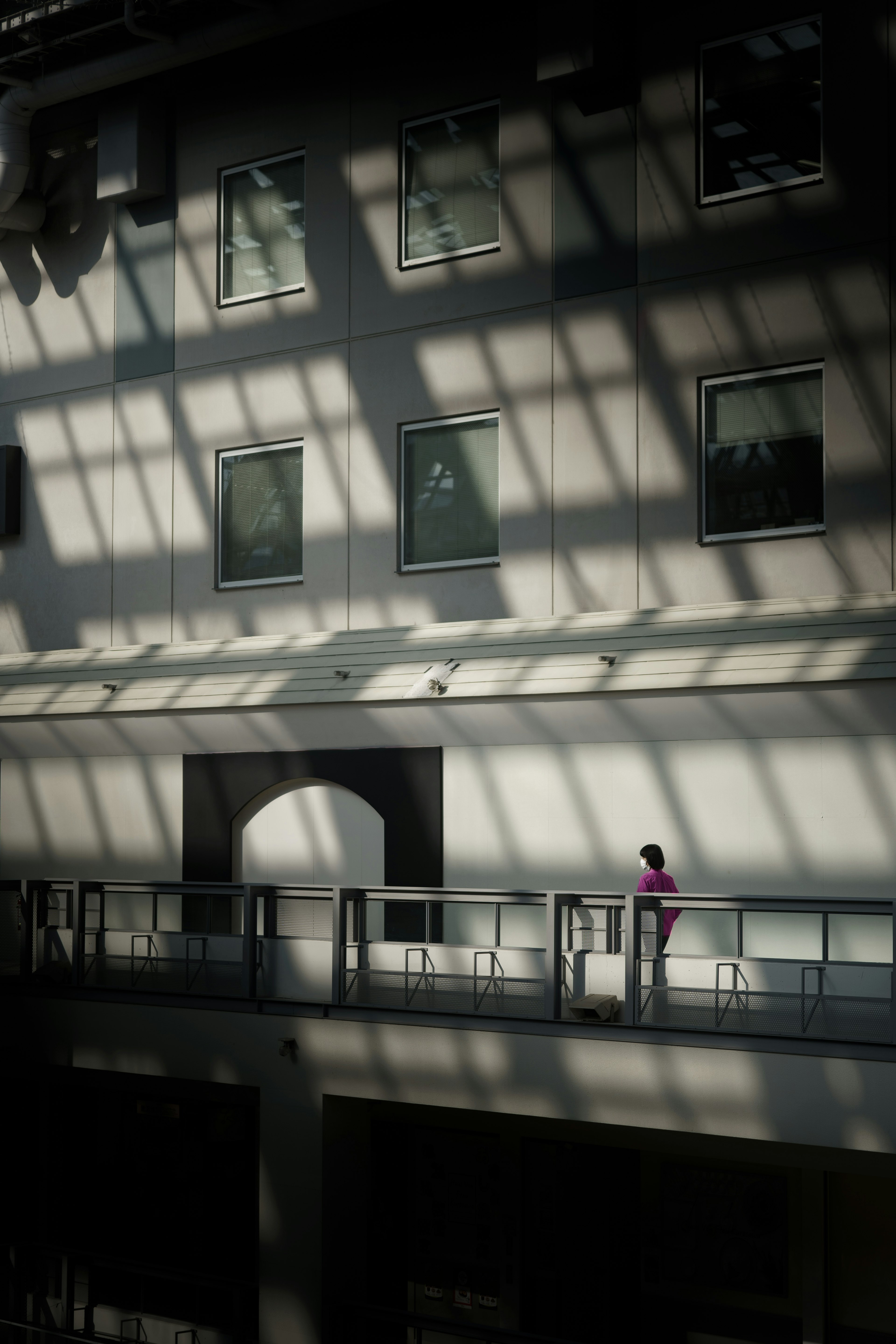 Une femme se tenant sur un balcon avec des ombres projetées sur le mur