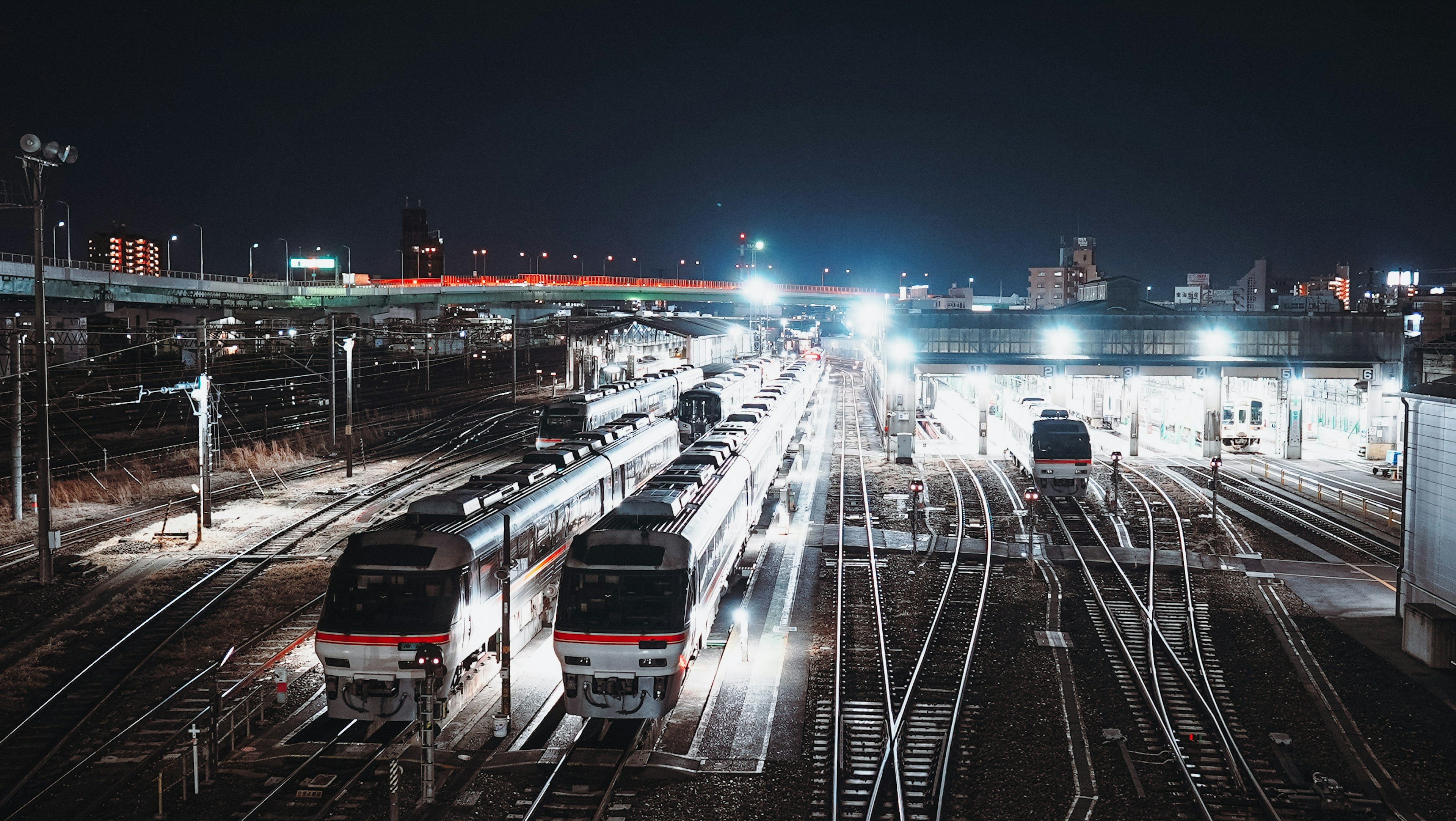 Pemandangan malam kereta di stasiun dengan pencahayaan terang dan rel