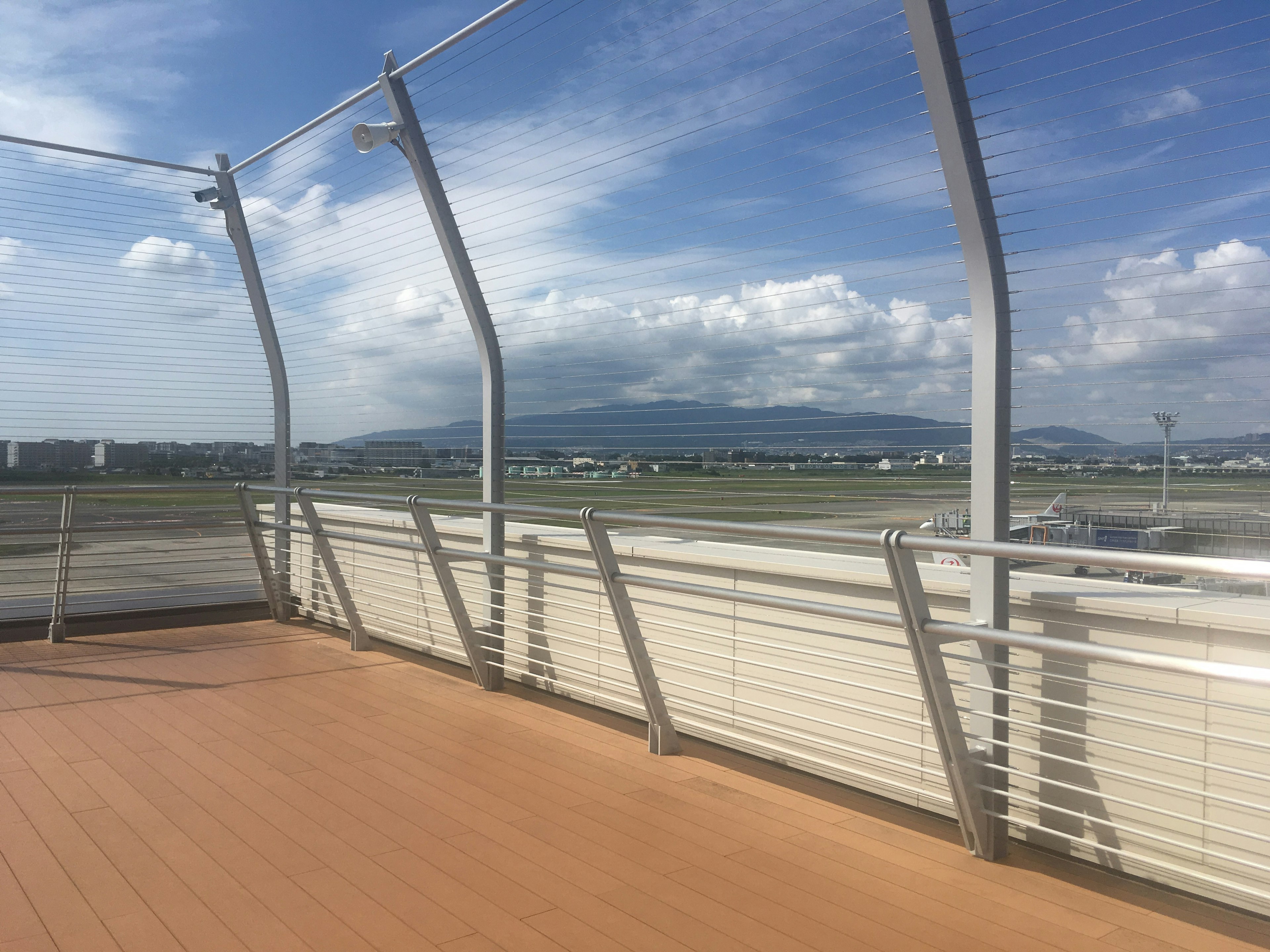 Vue depuis une terrasse d'observation d'aéroport montrant la piste et les montagnes