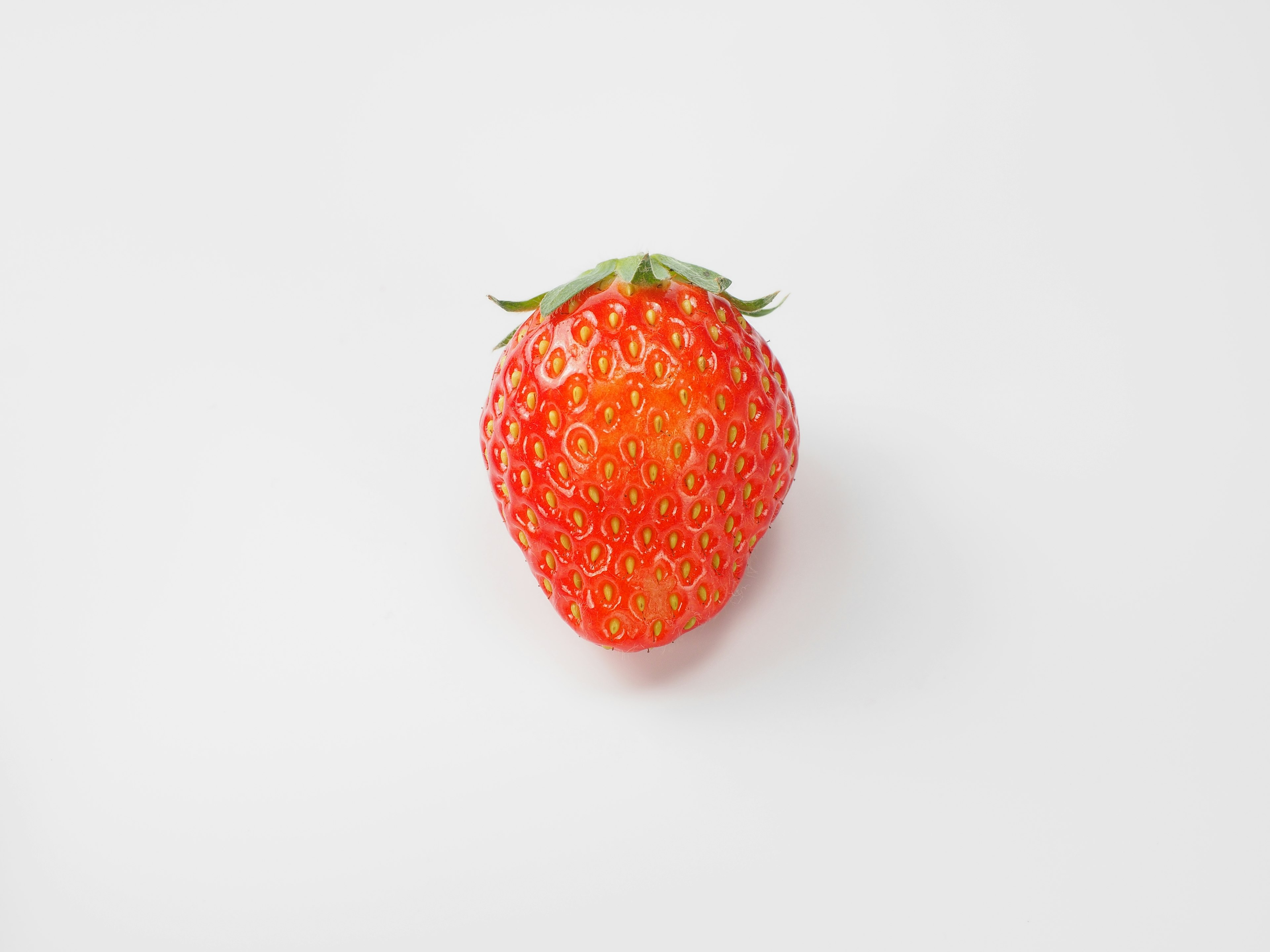 A vibrant red strawberry placed on a white background