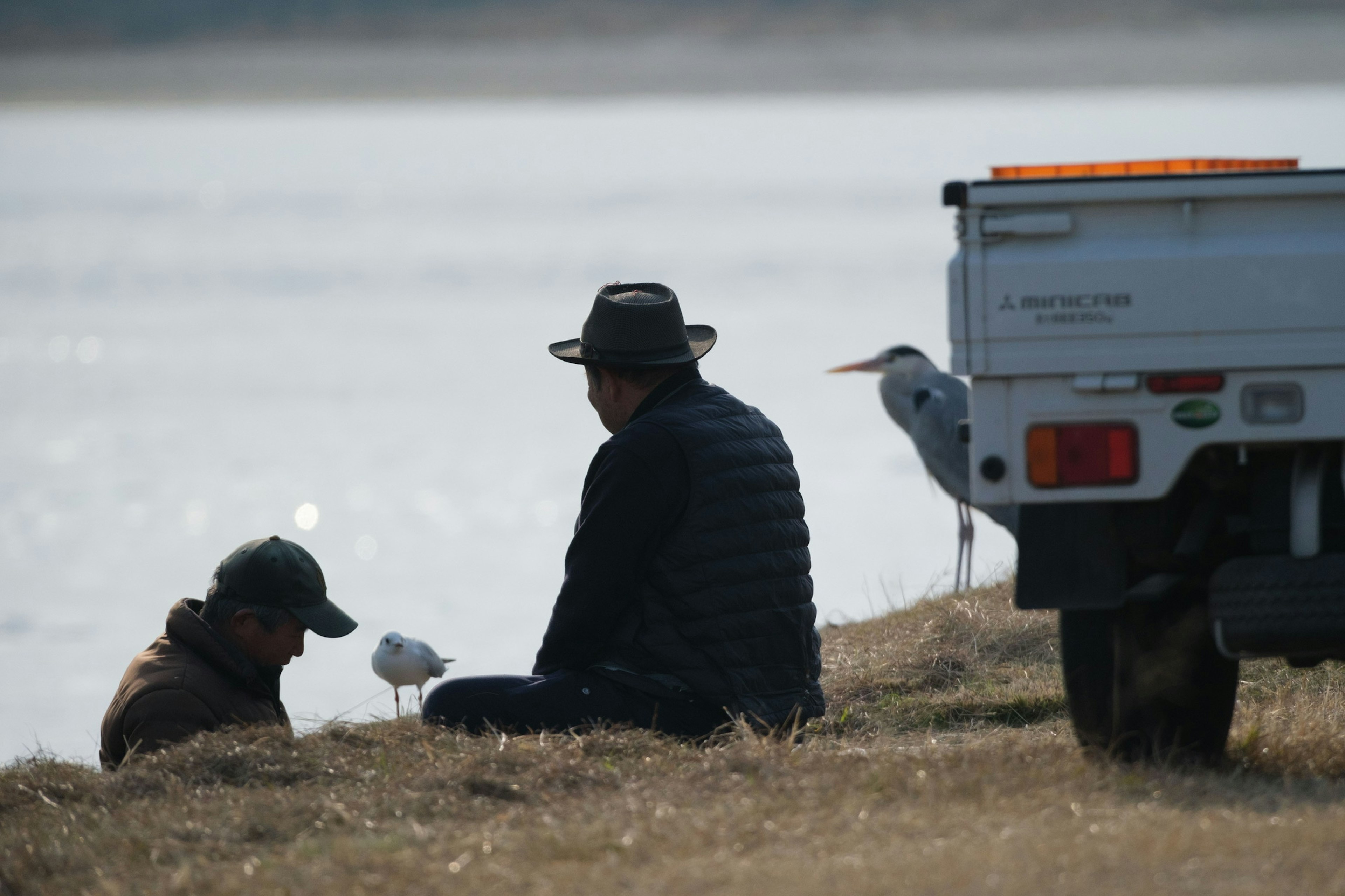 二人の男性が水辺で座っている様子とトラックの一部