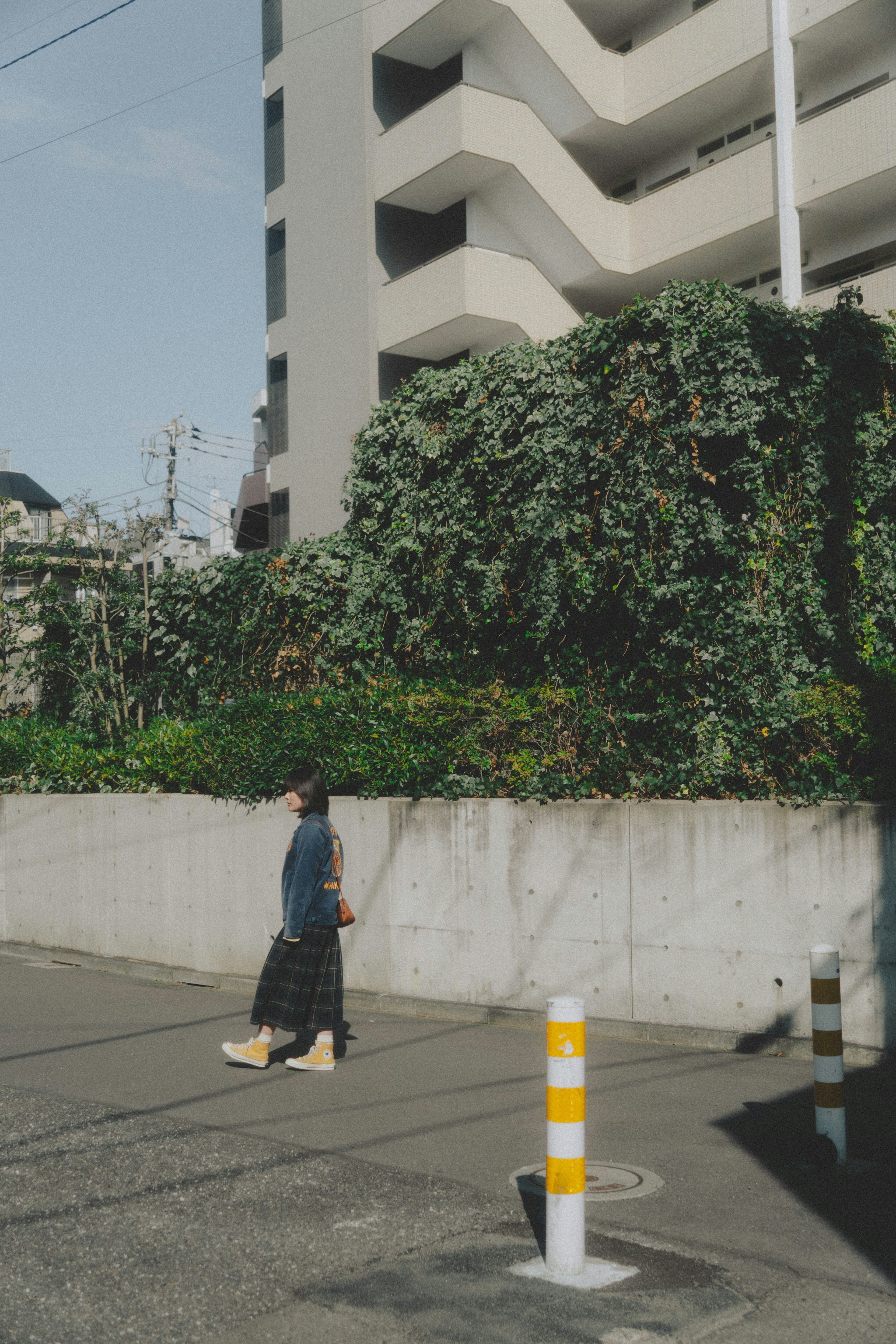 Woman walking in front of a lush green wall and a modern building