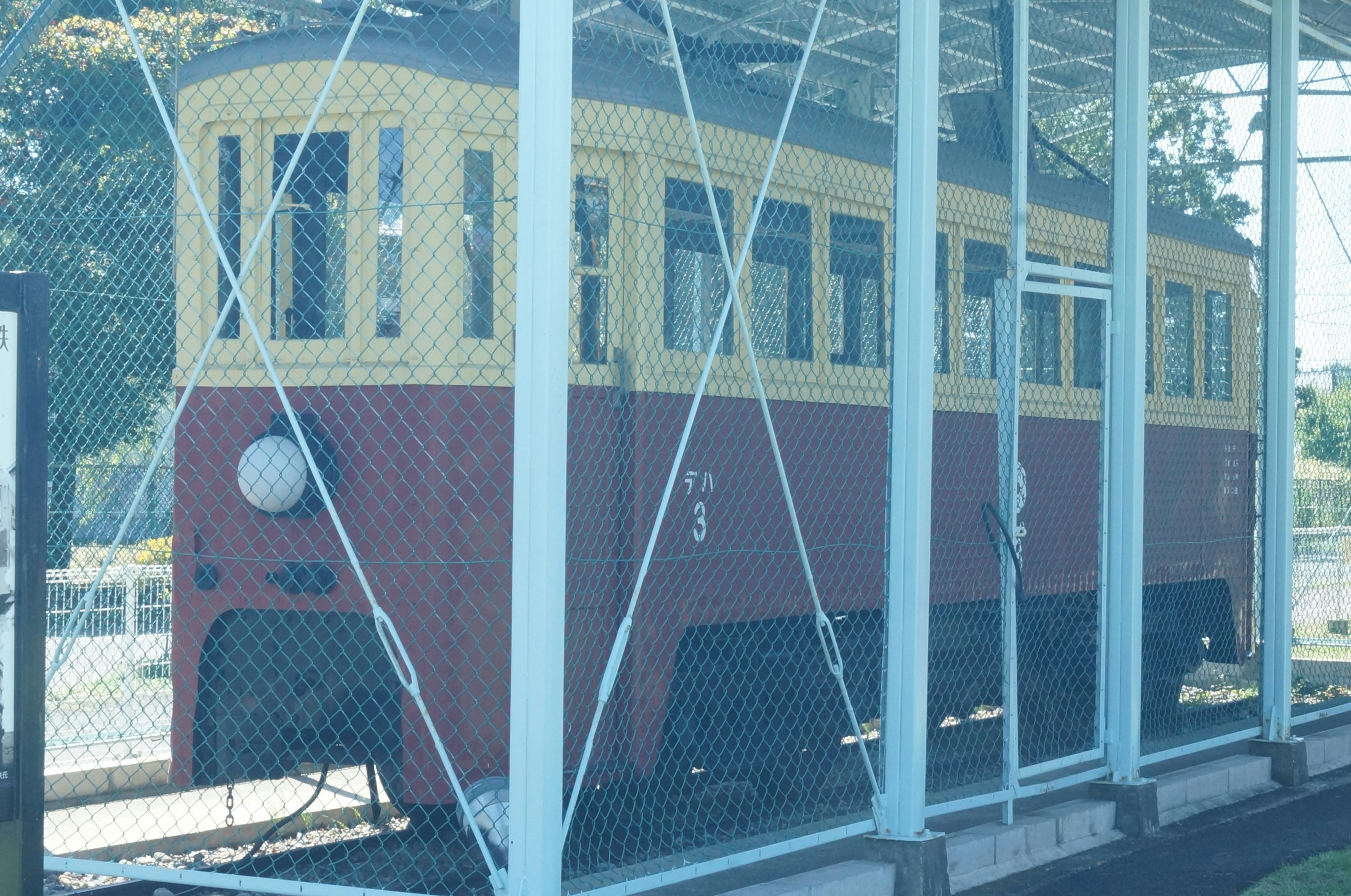 An old red and yellow train displayed within a fence