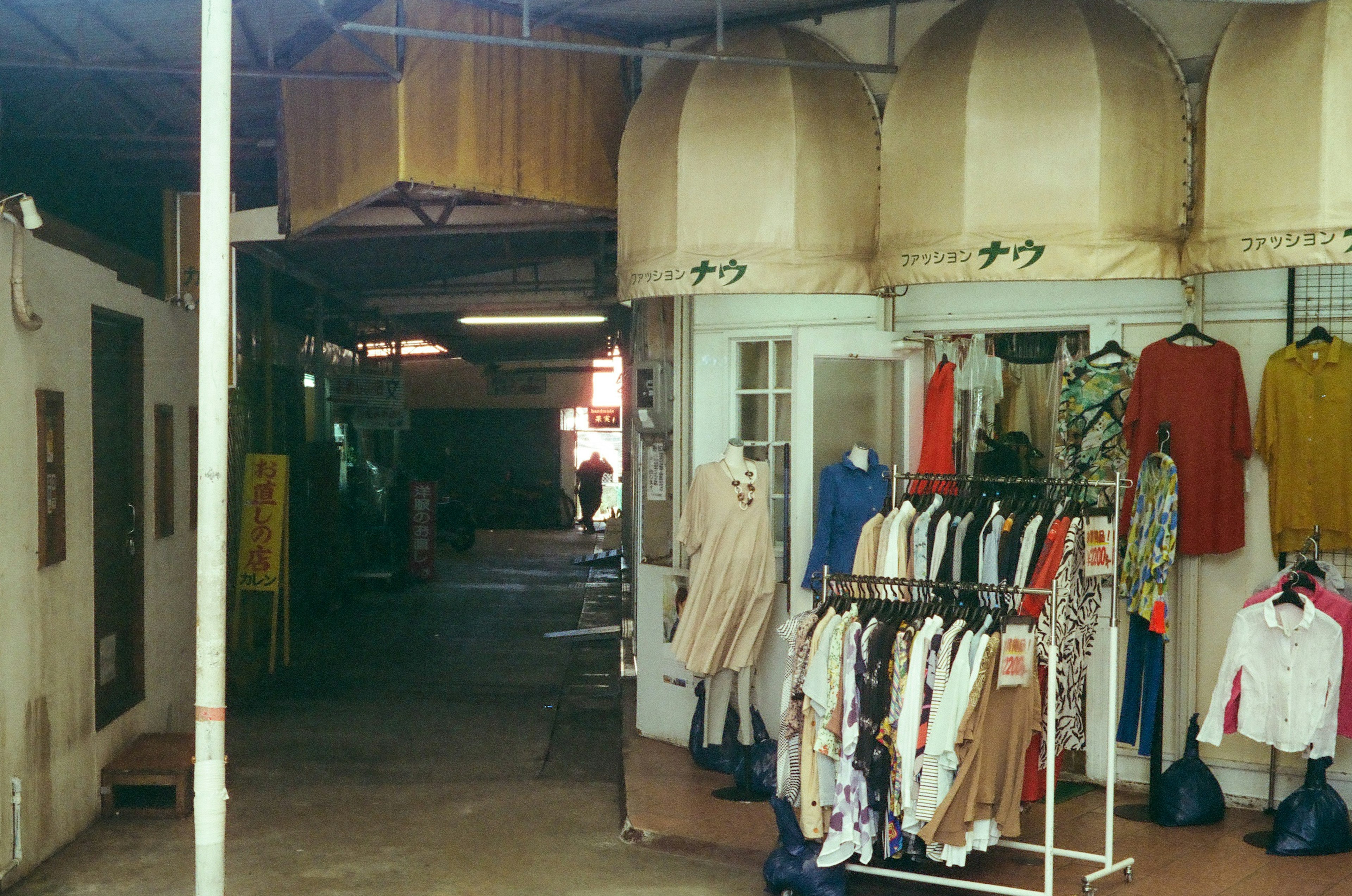 Escena de tiendas de ropa dentro de un arcade de mercado con toldos colgantes