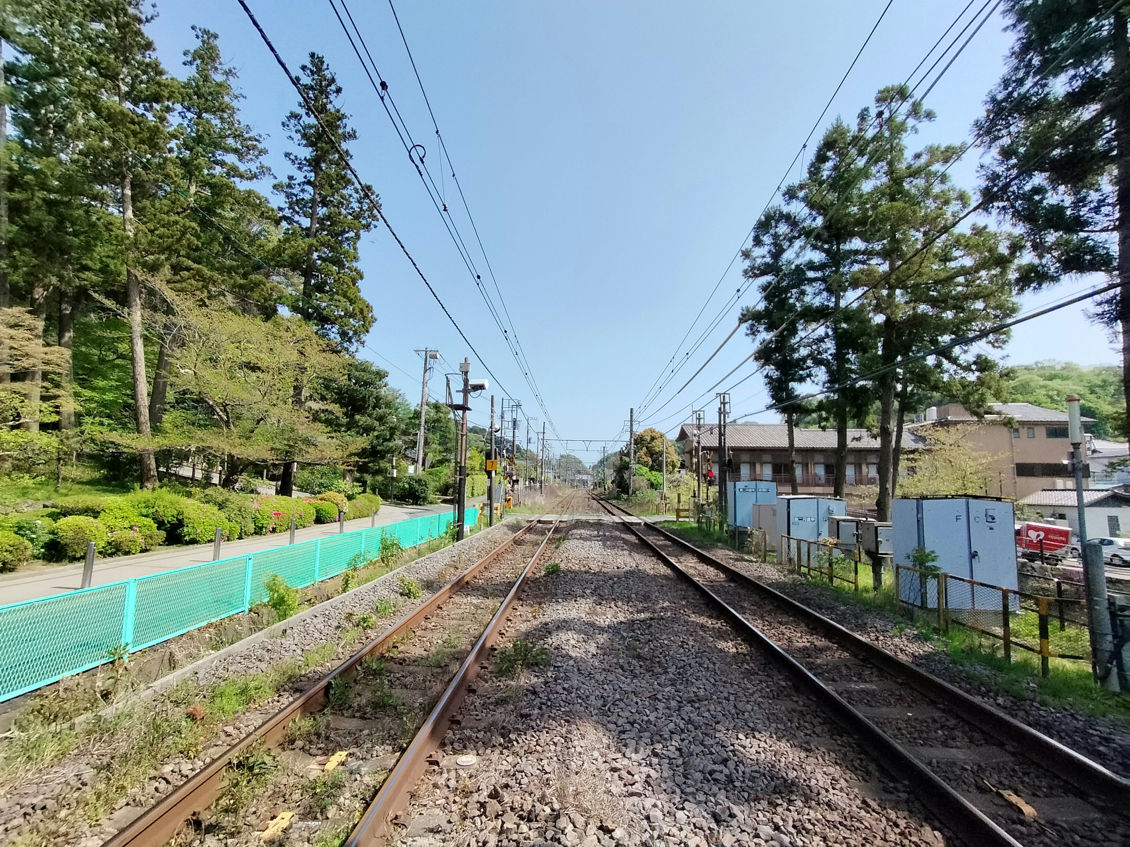 Vista dei binari ferroviari con alberi ai lati cielo azzurro e vegetazione lussureggiante