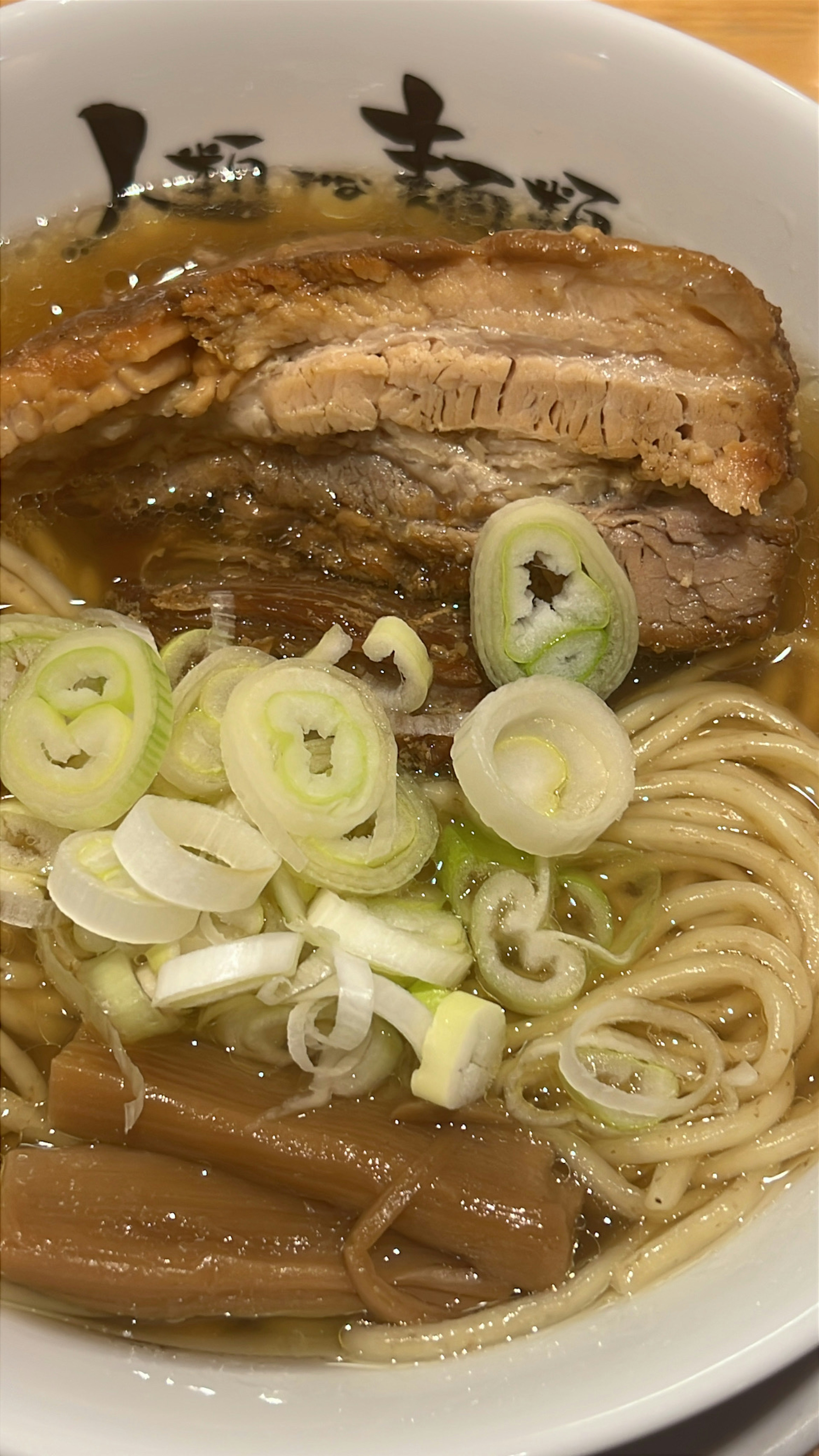 얇게 썬 돼지고기와 파가 얹힌 맛있는 라멘 한 그릇