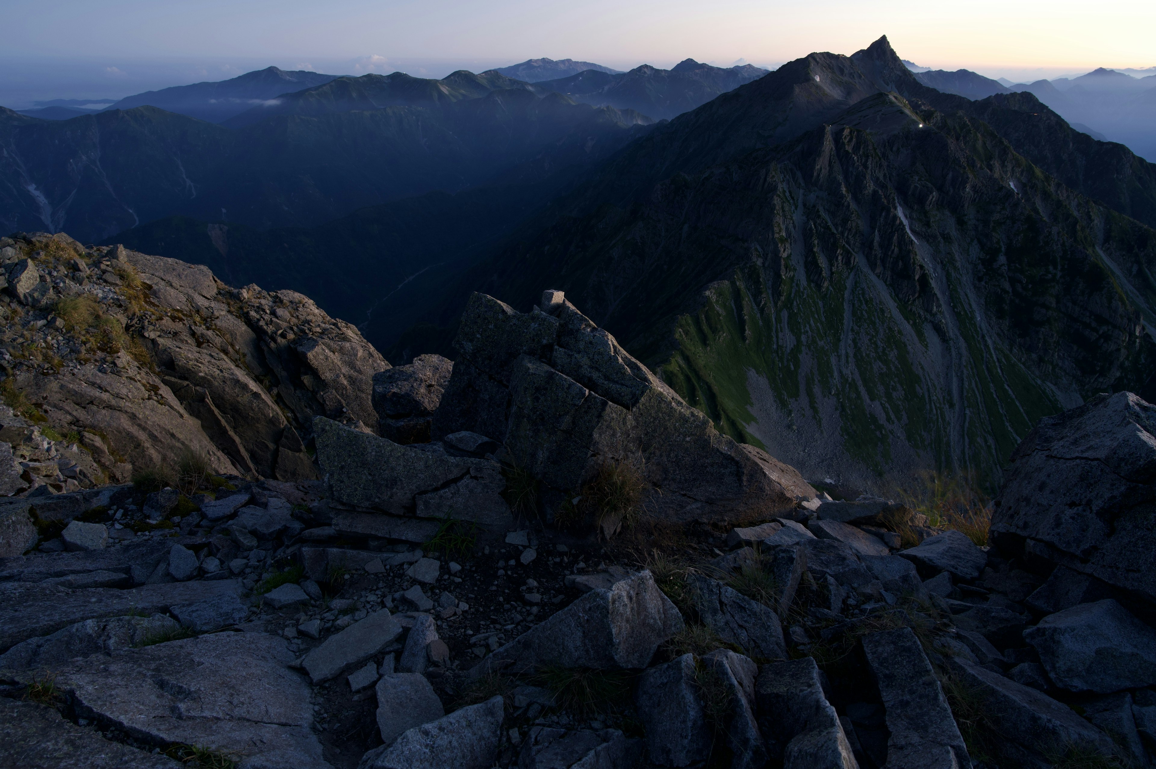 Vista panoramica da una cima di montagna con rocce e montagne lontane al crepuscolo