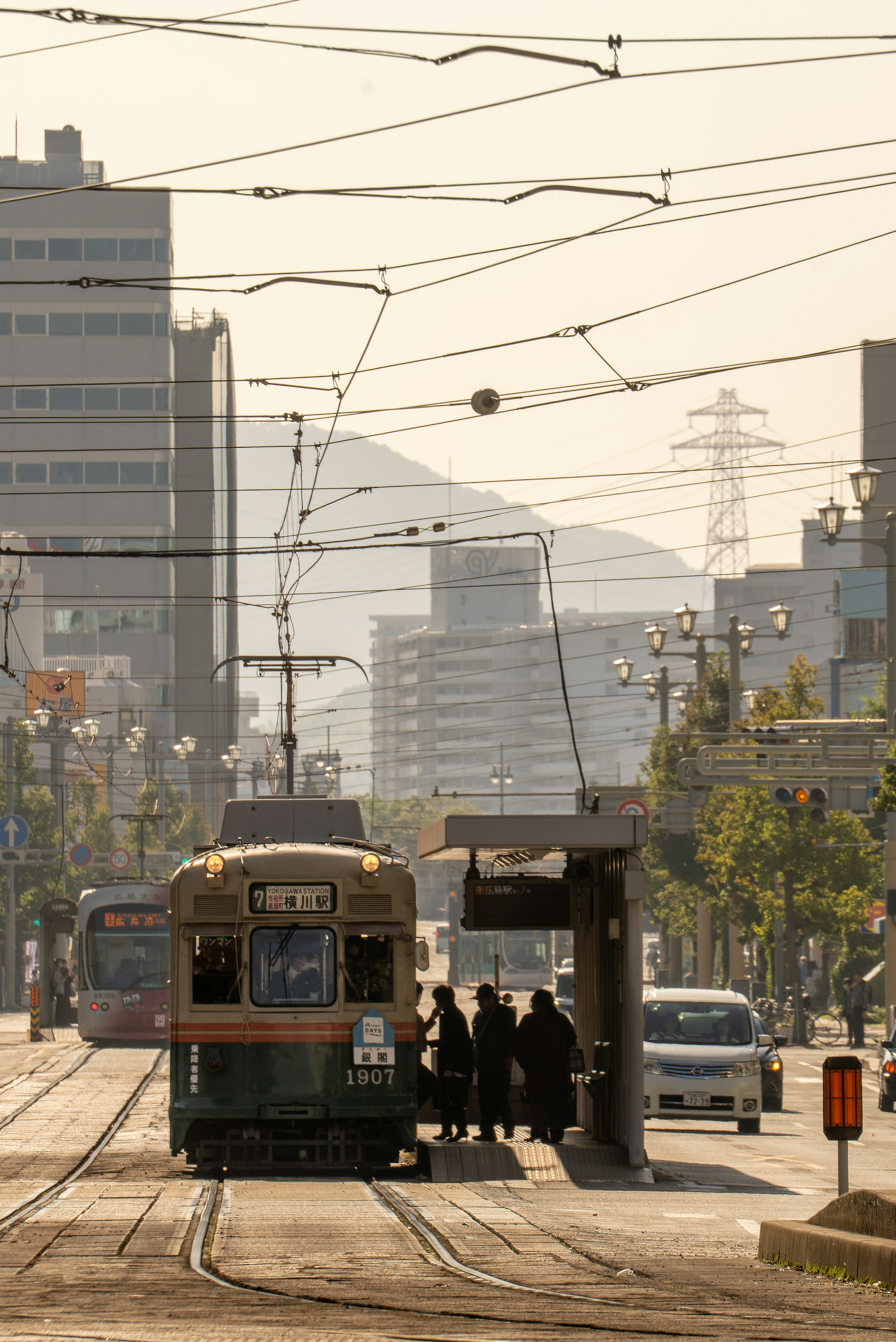 Une scène de rue avec un tram s'arrêtant pendant que des gens montent au crépuscule