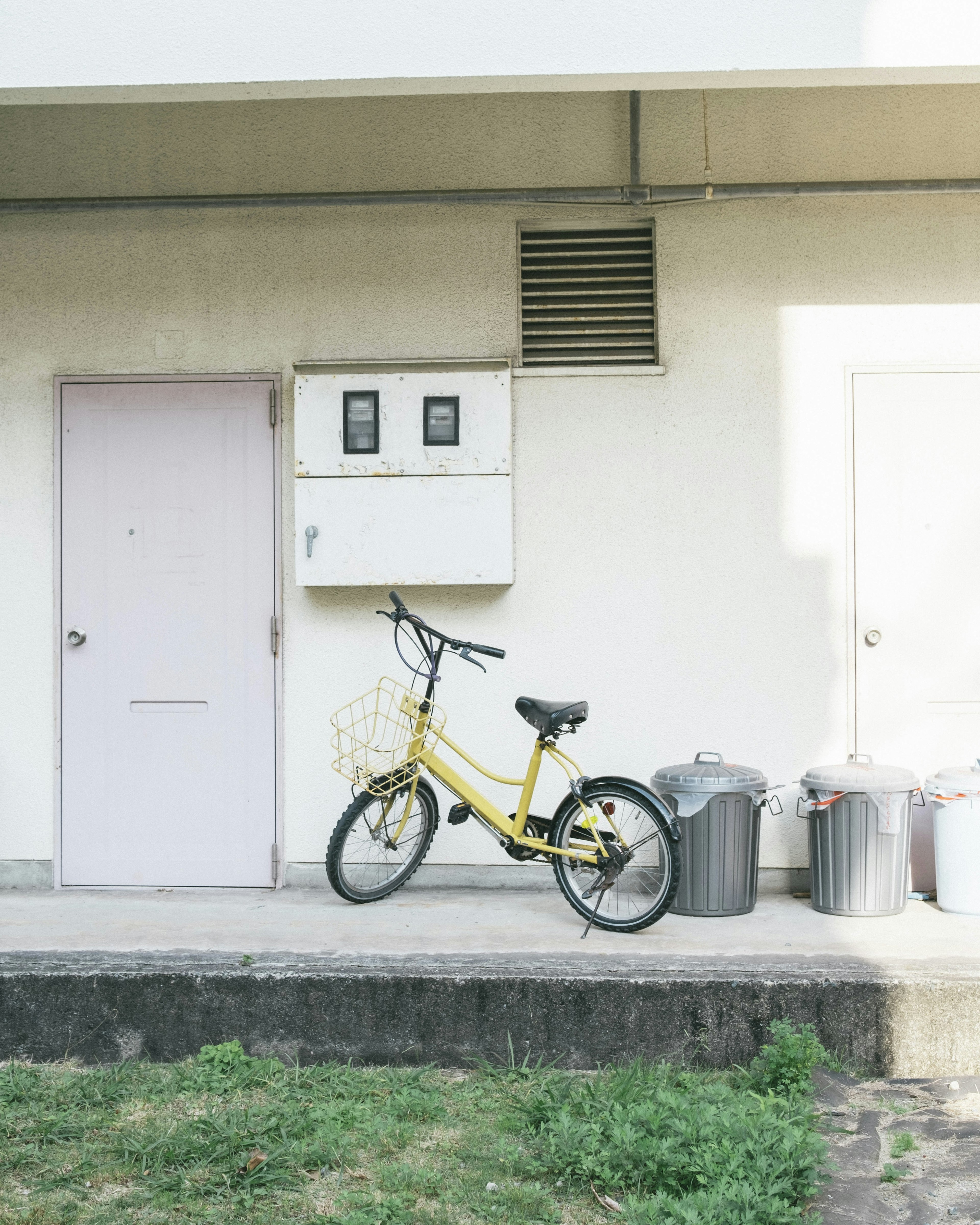 Sebuah sepeda kuning bersandar di dinding dengan lingkungan yang bersih