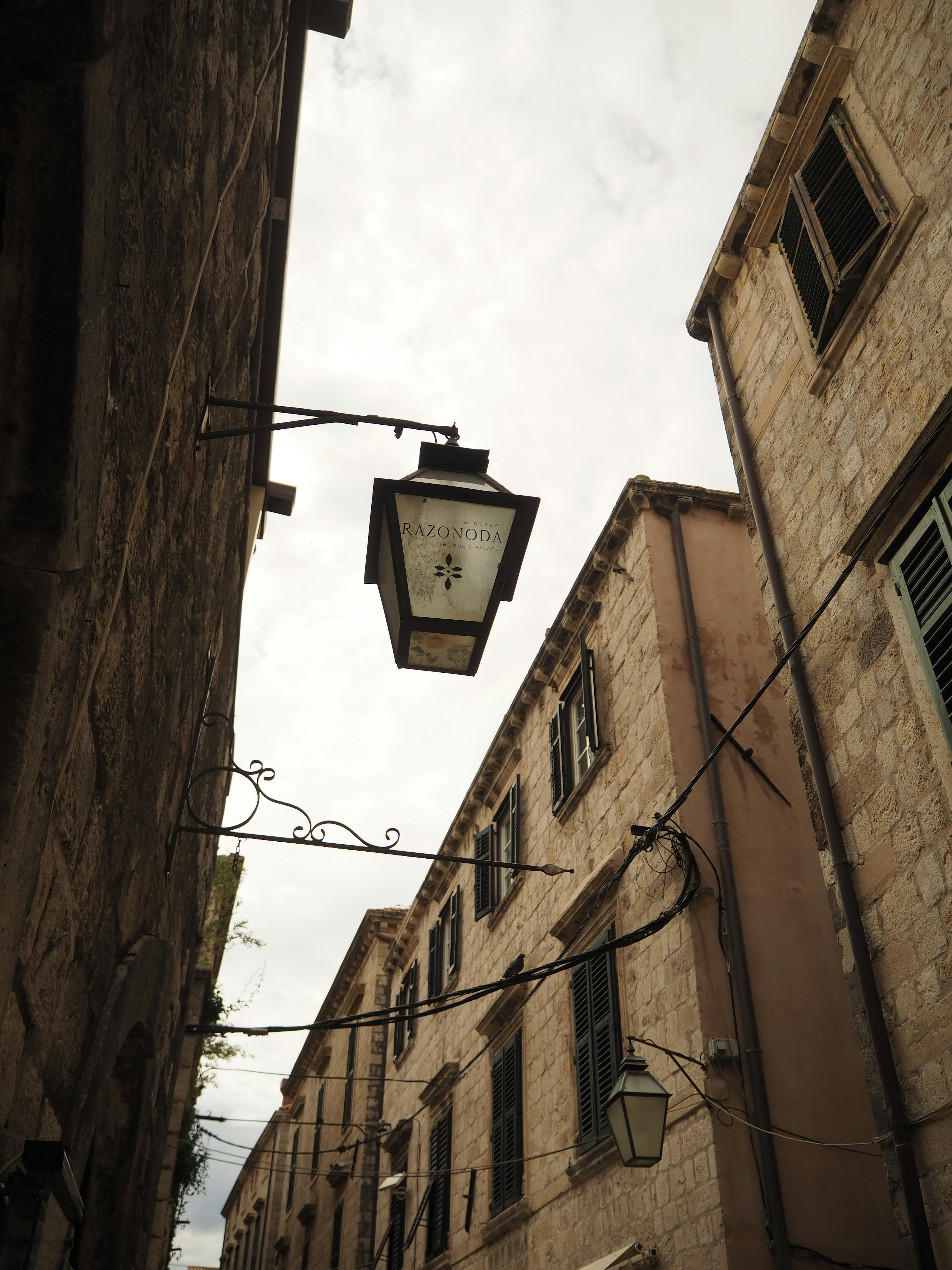 Callejón estrecho con edificios de piedra y una farola decorativa