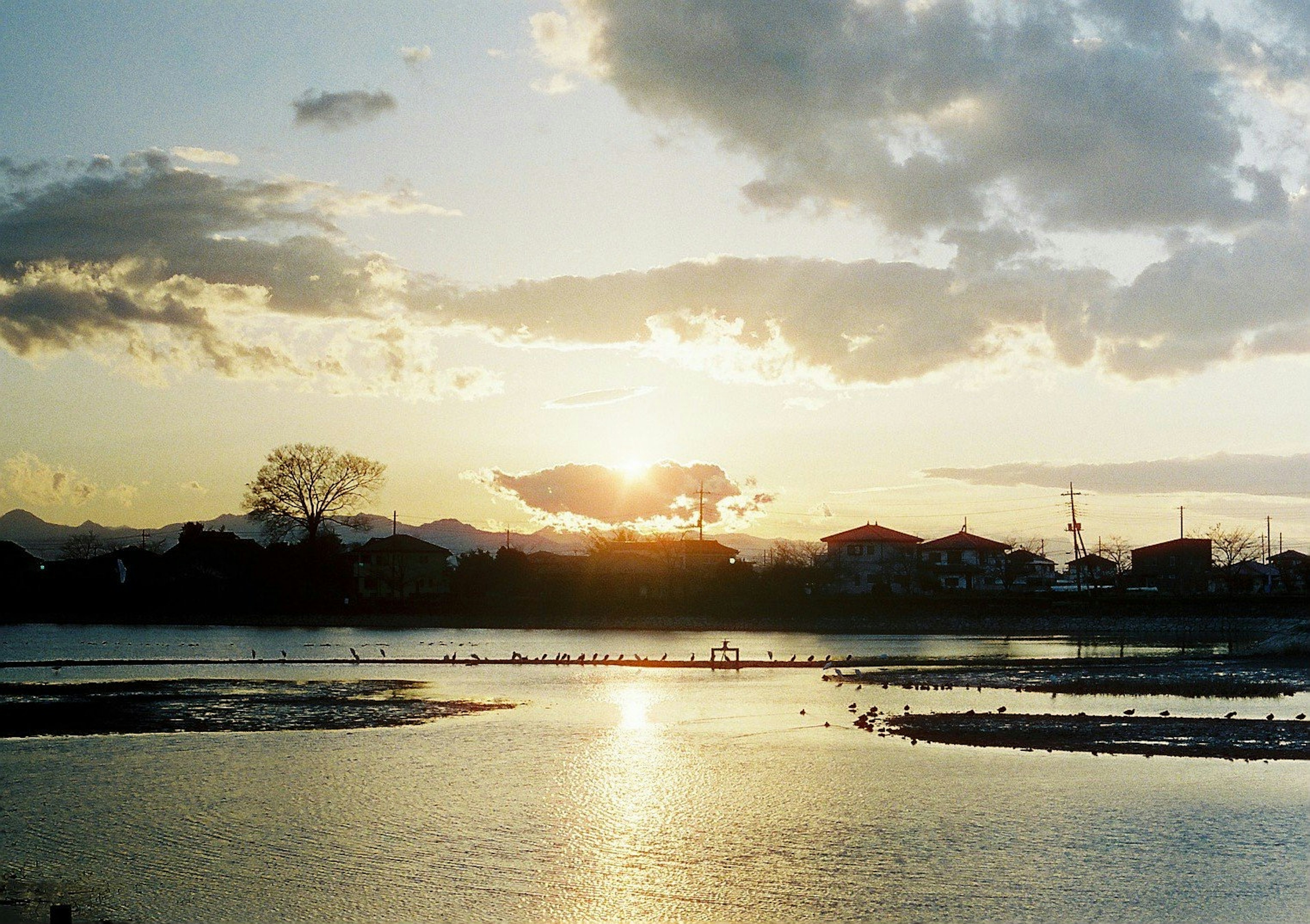 夕日が沈む河川の風景 山々と家々が見える