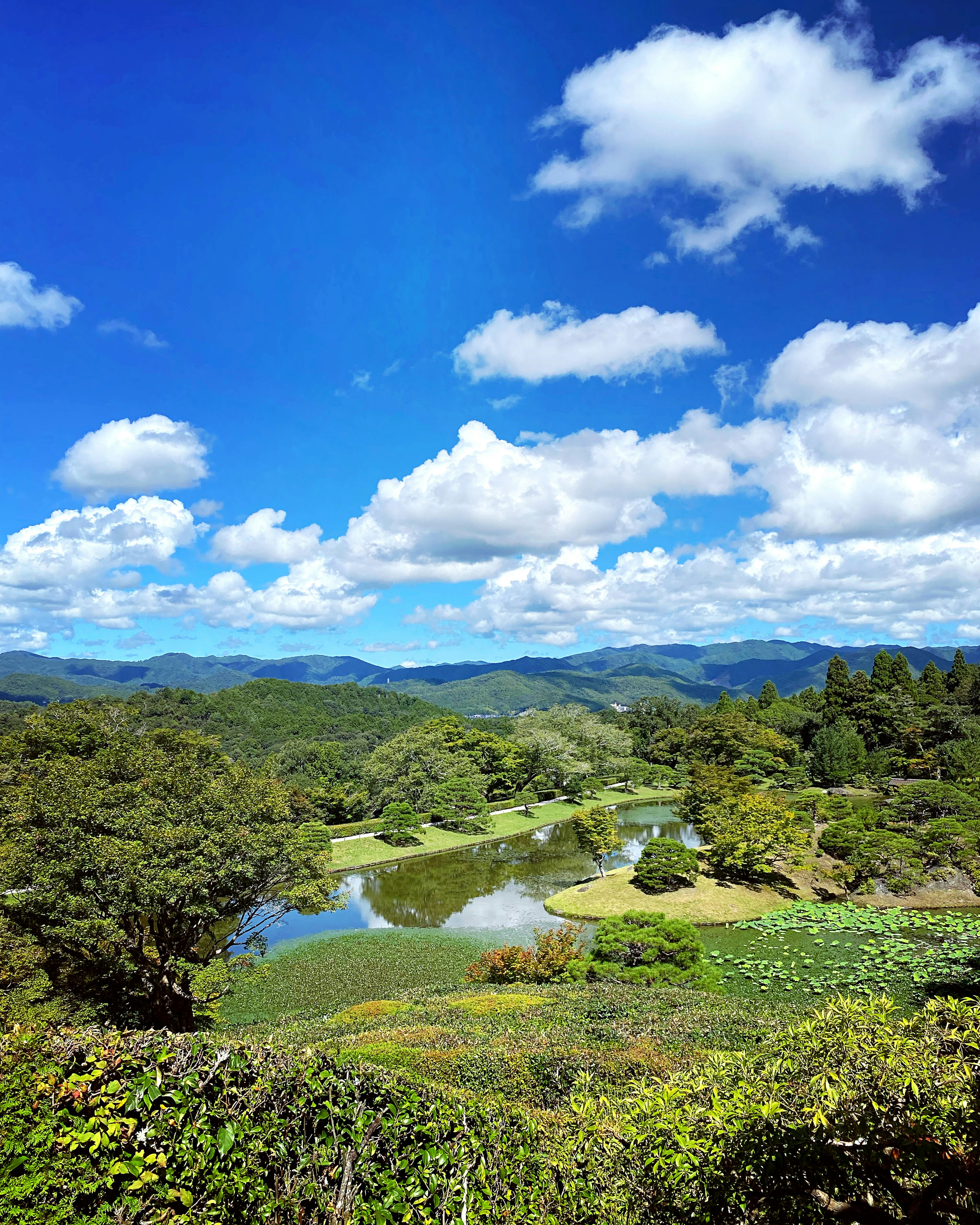 青い空と白い雲が広がる風景 緑豊かな山々と静かな湖