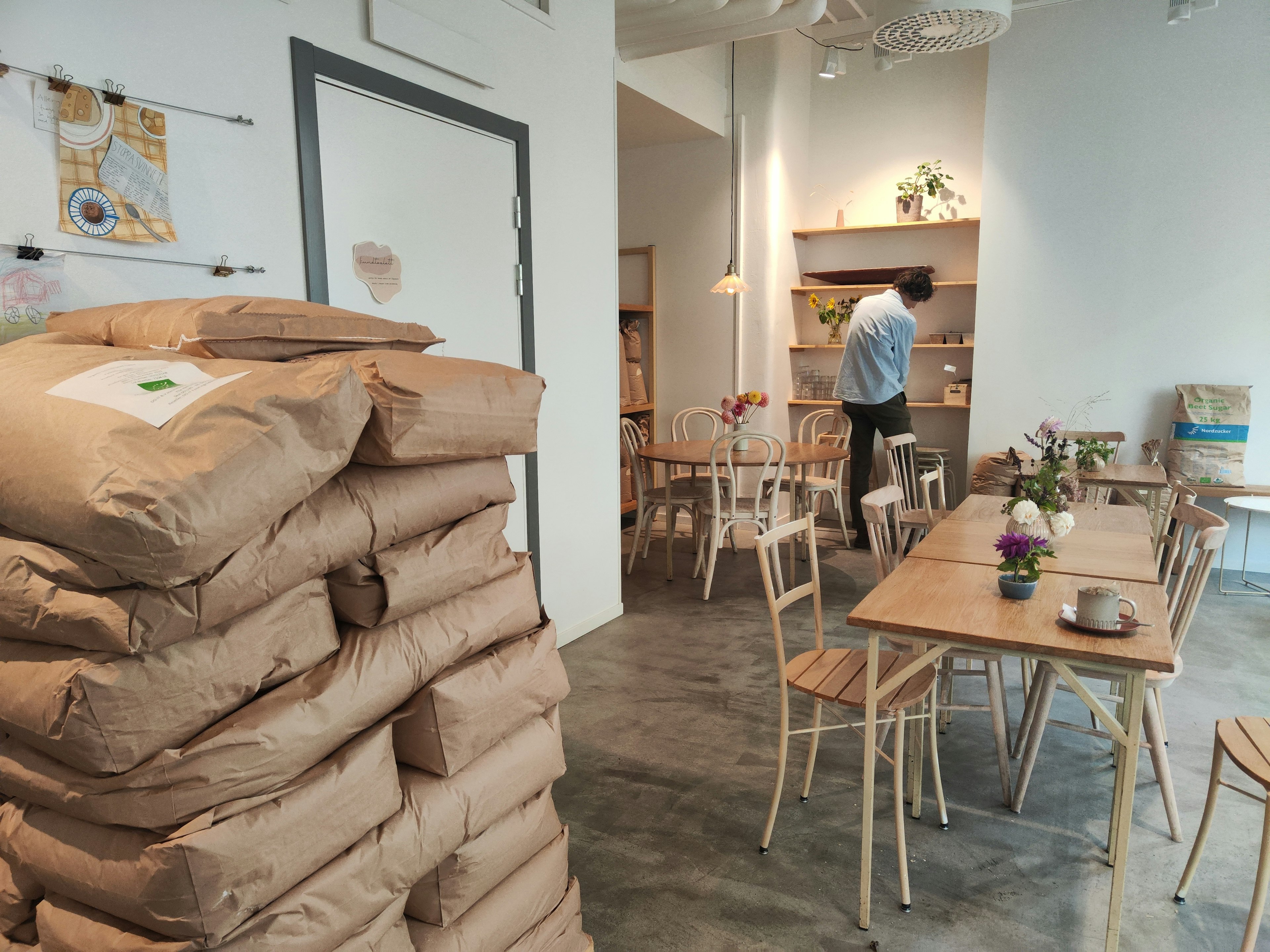 Interior de un café con sacos de yute apilados y mesas de madera