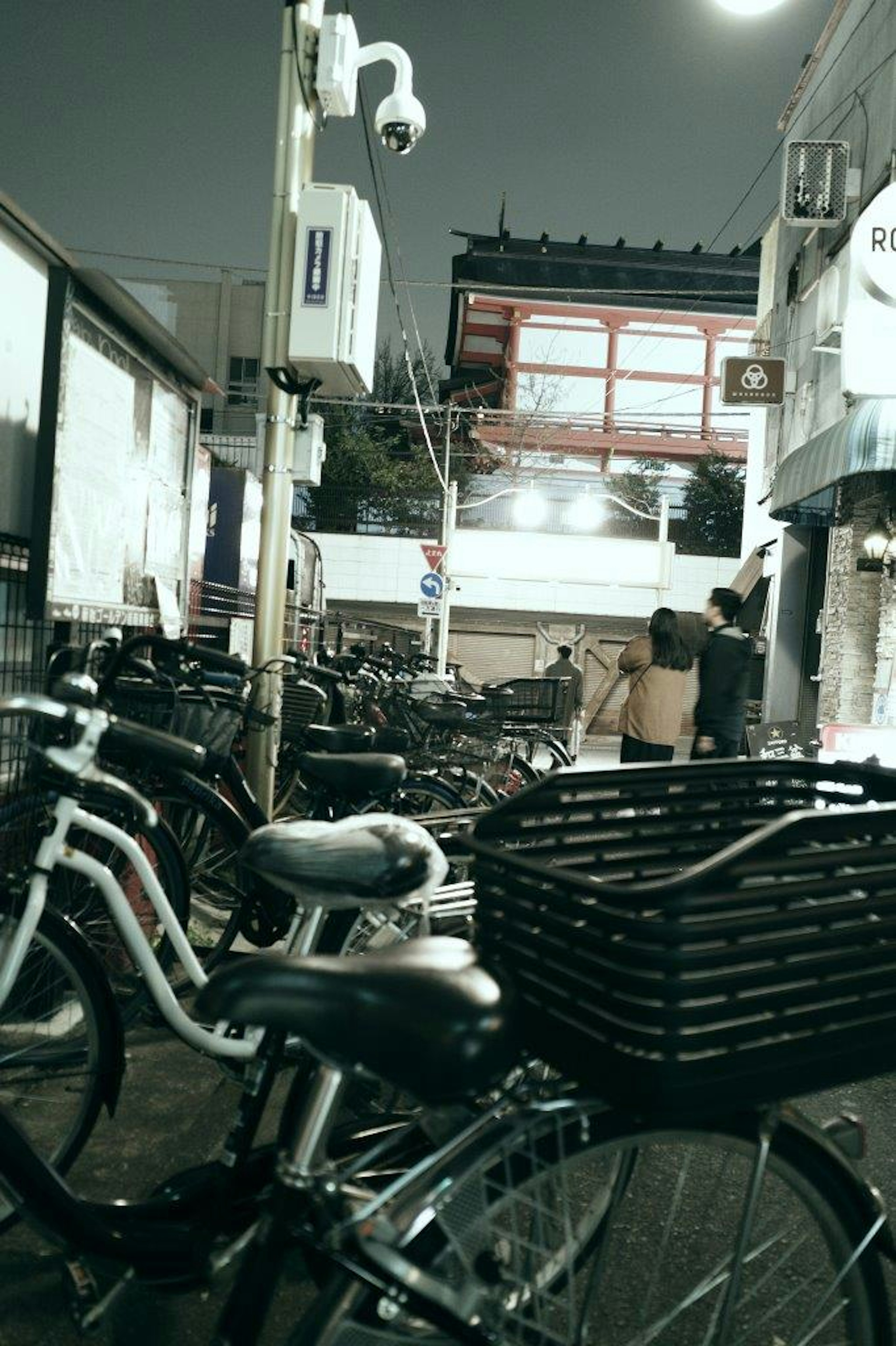 Bicicletas alineadas en una calle de la ciudad por la noche con una puerta roja al fondo