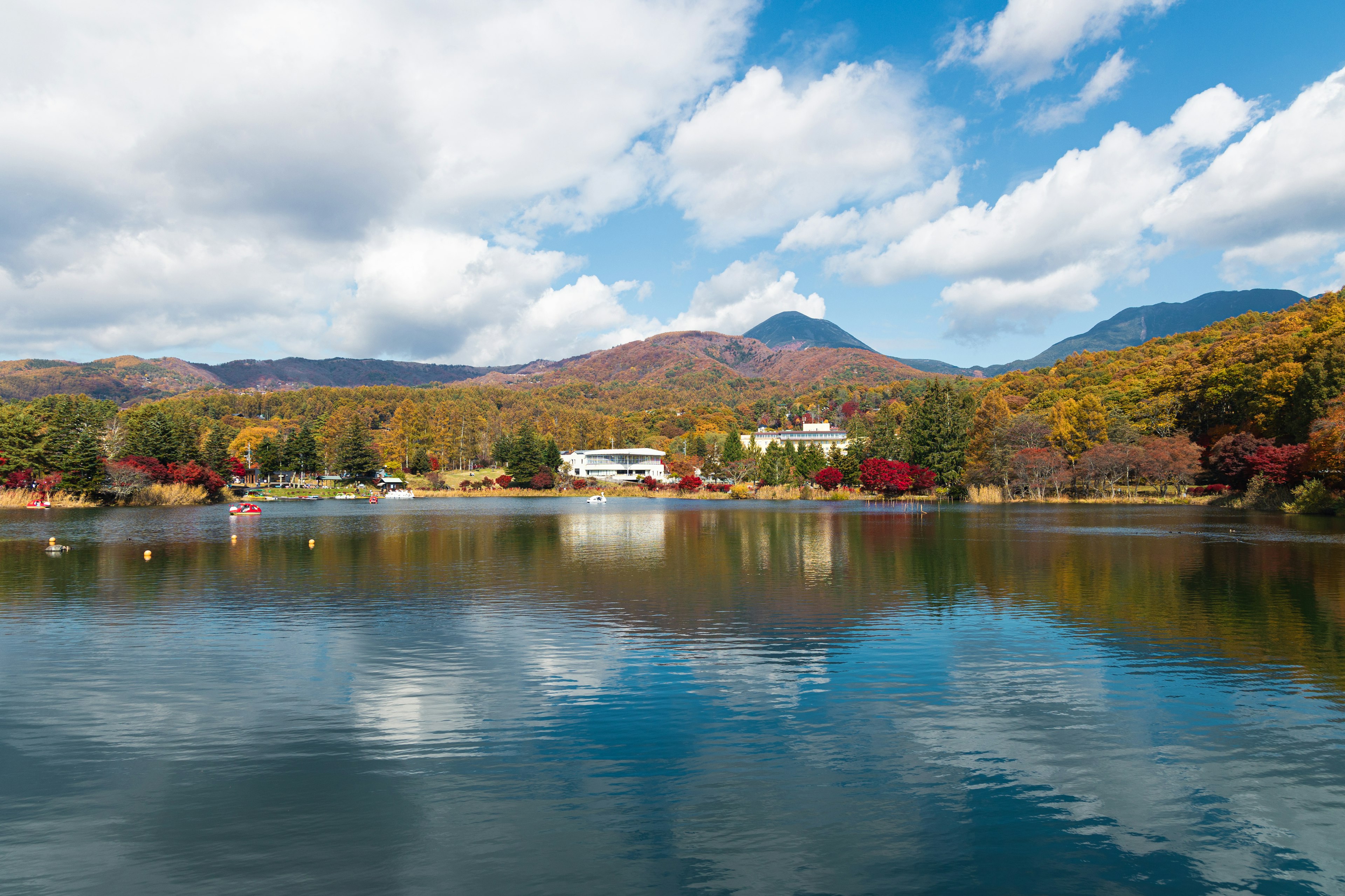 Vista escénica de un lago que refleja árboles de otoño coloridos y montañas