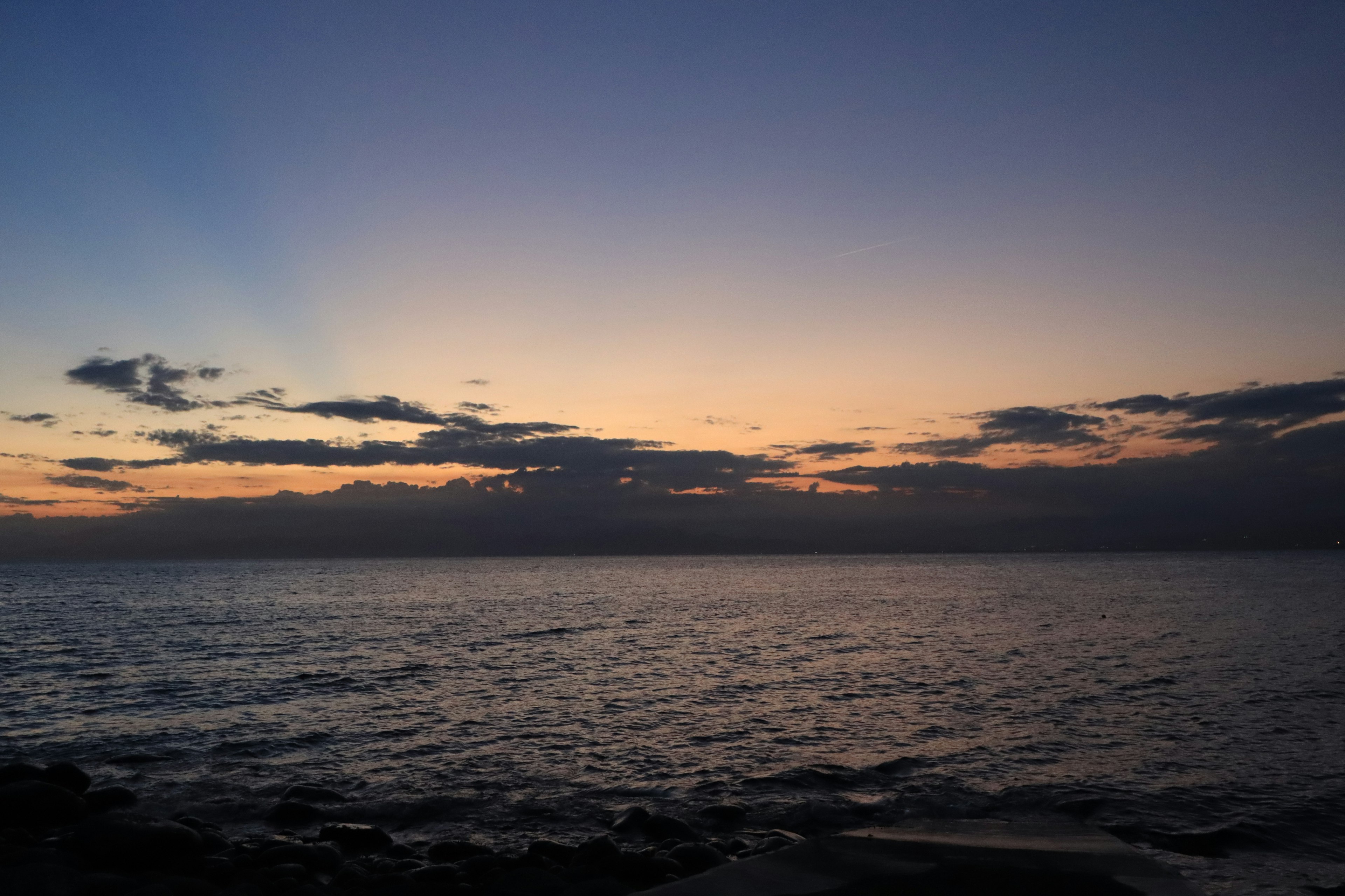 Beautiful sunset over the ocean, orange and blue hues, calm waves, clouds in the sky