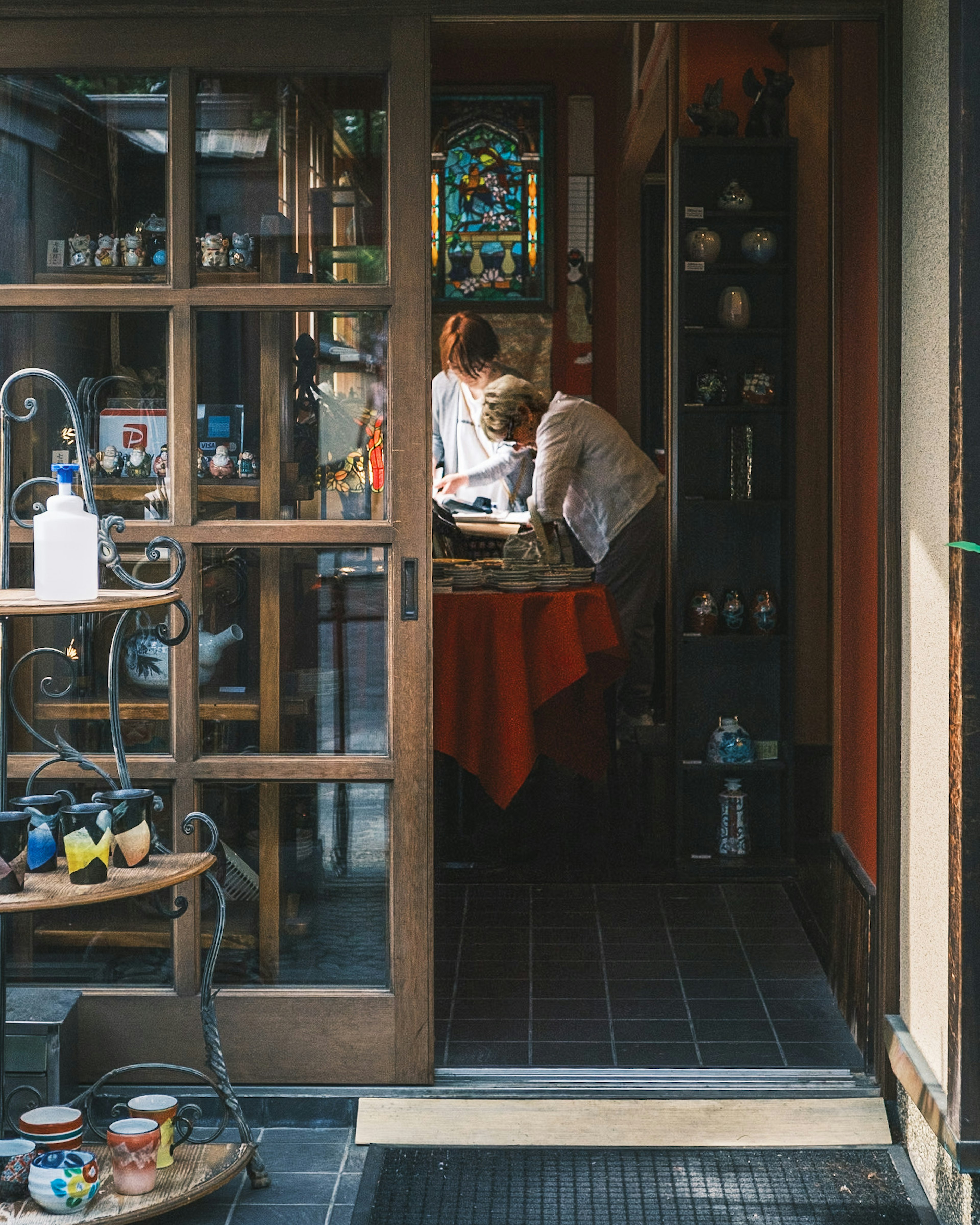 Entrée d'un magasin vintage avec deux personnes à une table et de la poterie colorée