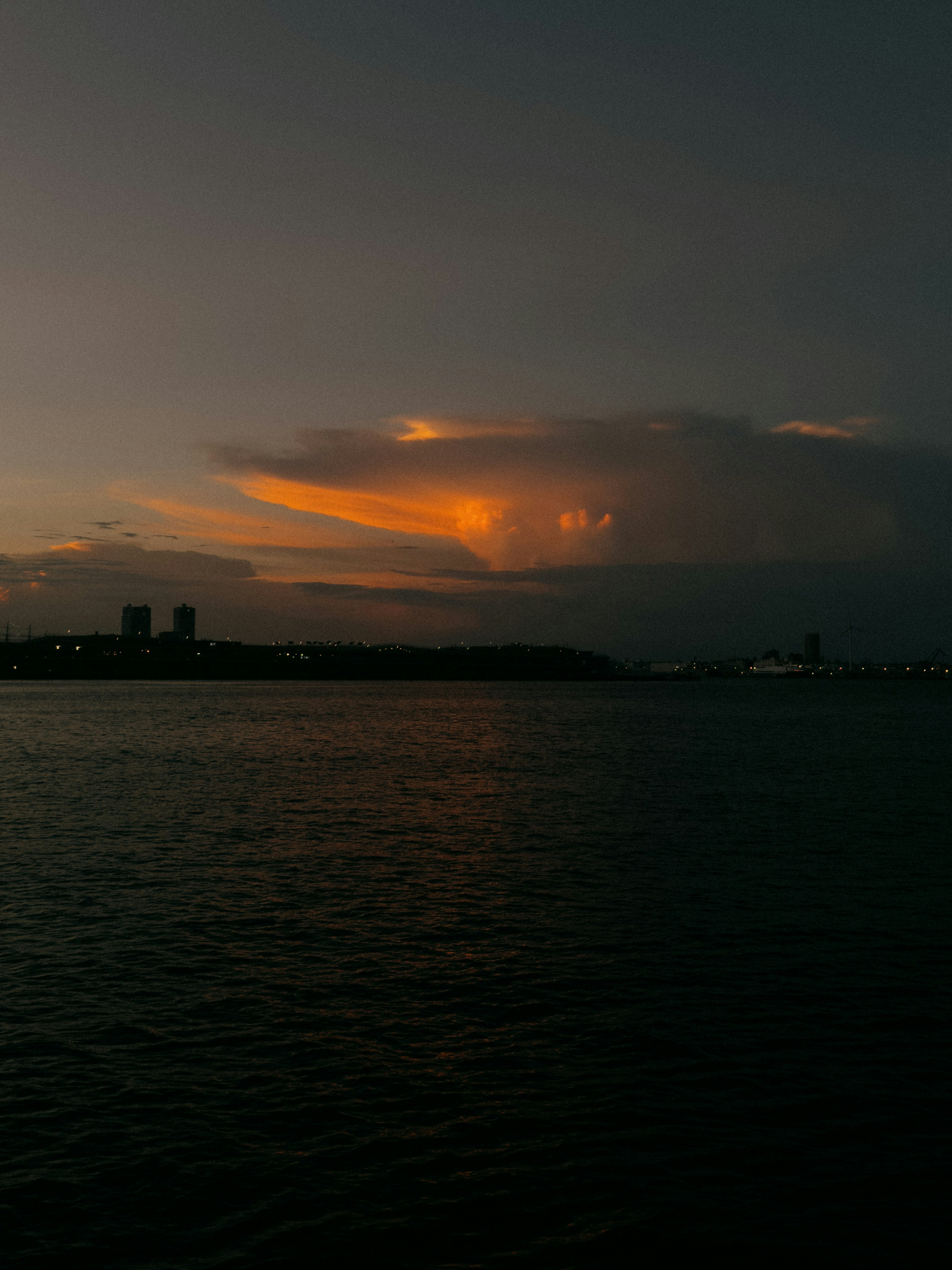 Orange sunset glowing between clouds over the ocean at dusk