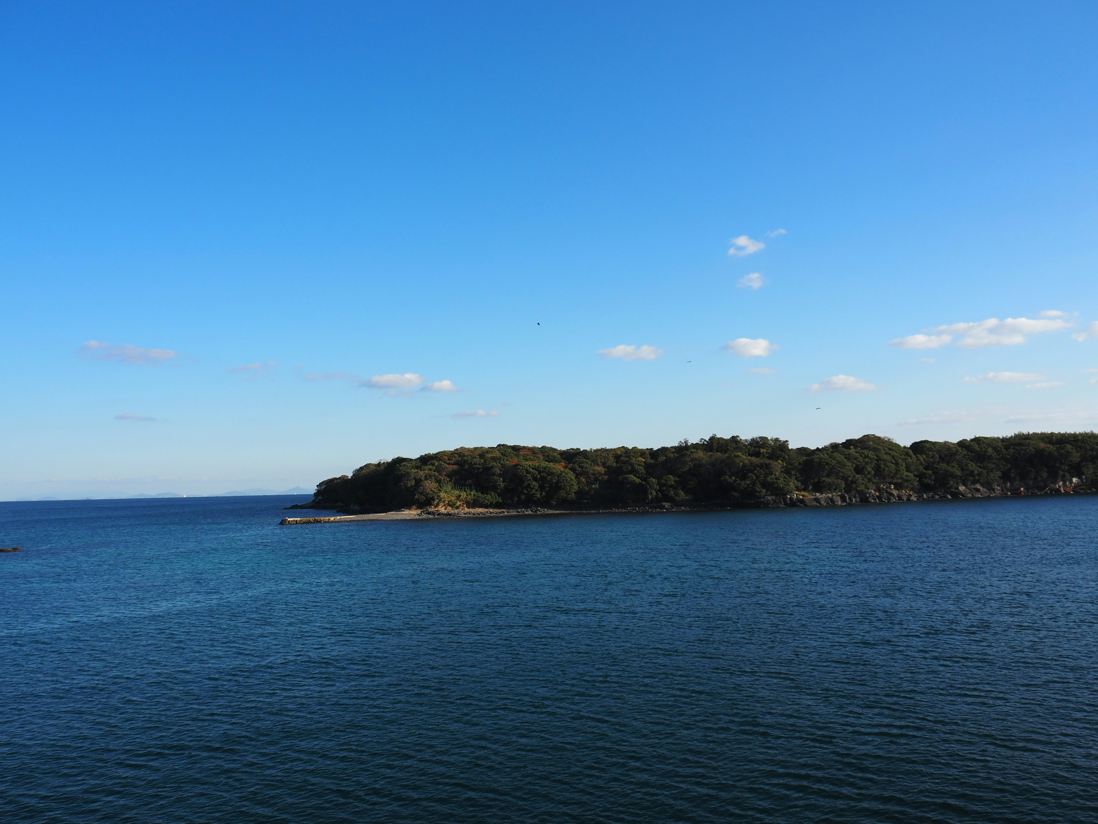 Vista panoramica di un cielo blu e un mare calmo con un'isola verdeggiante