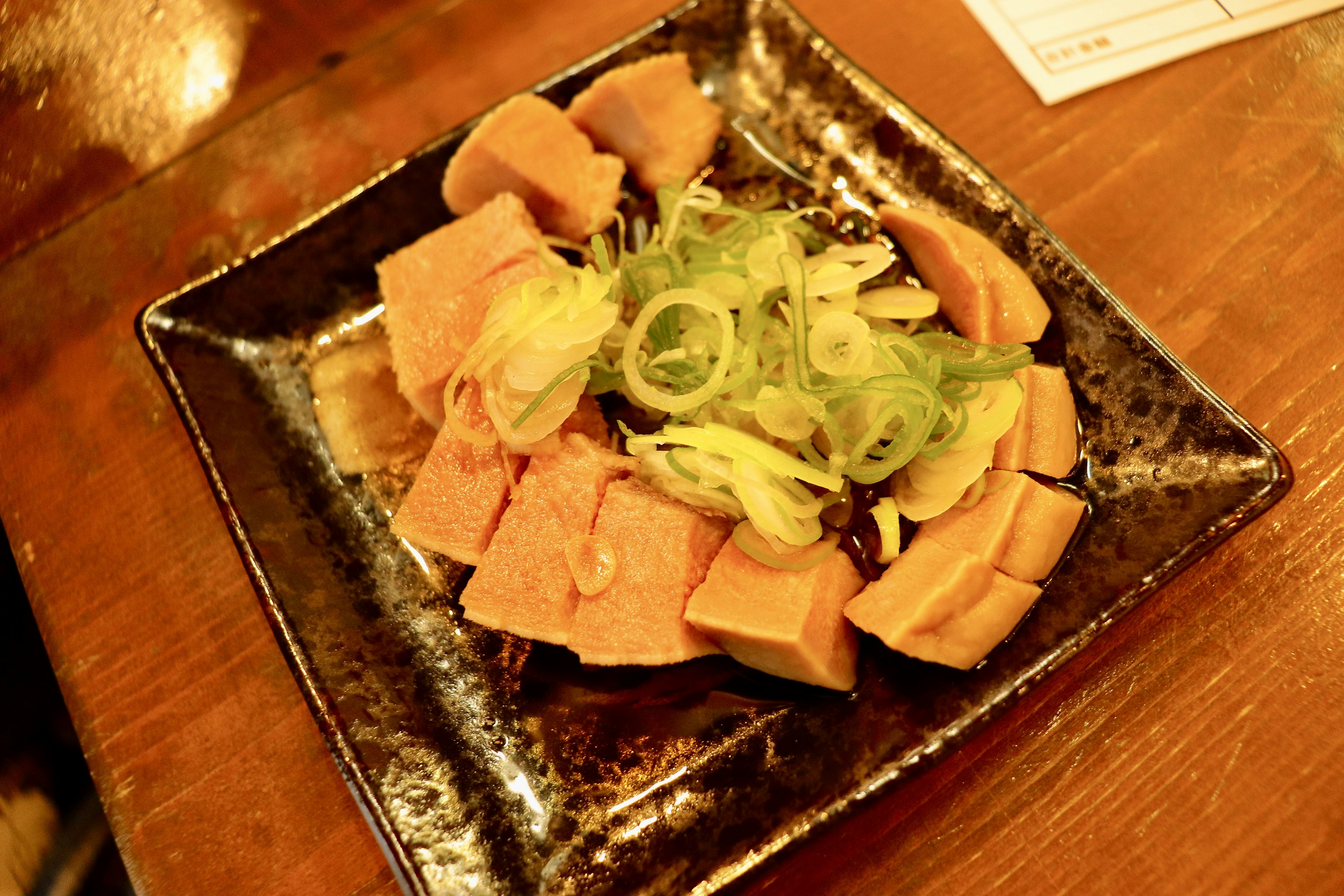 Tranches de spam sur une assiette noire avec une salade d'oignons verts