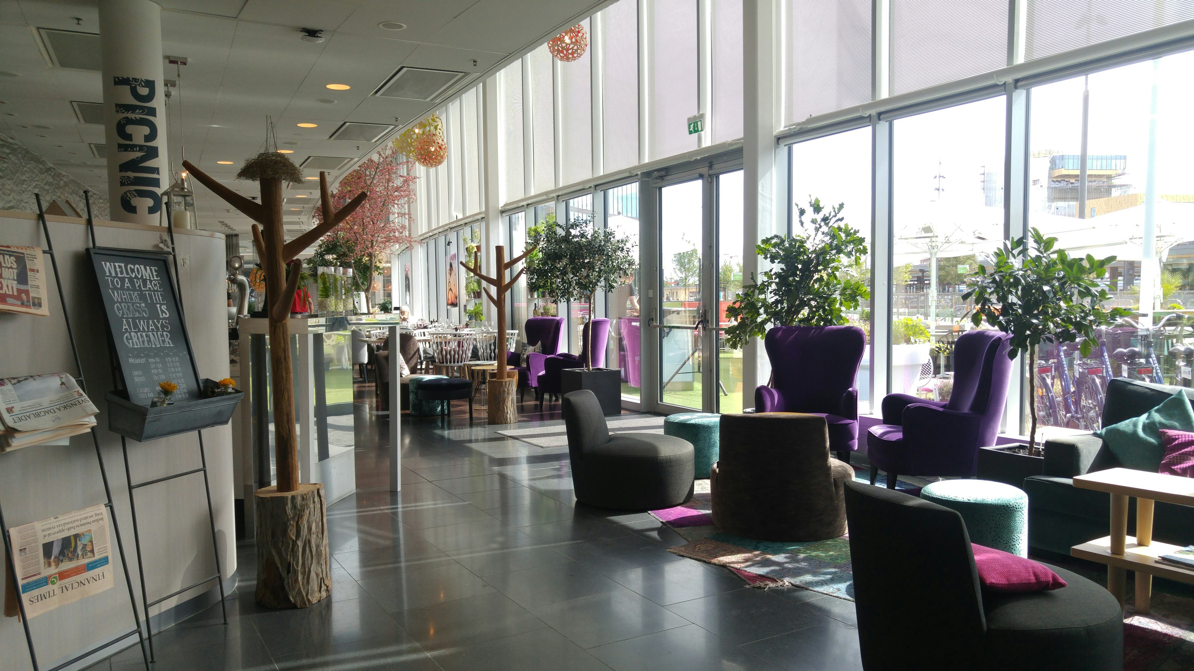 Interior de café brillante con muchas plantas y asientos cómodos