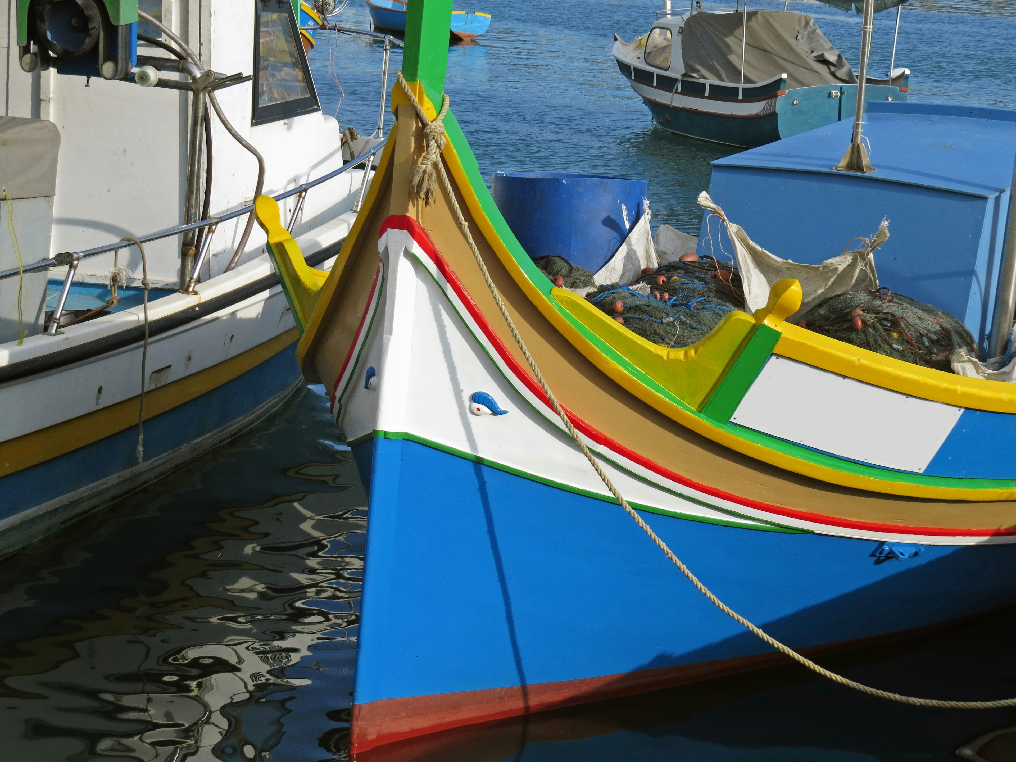 Proa de un colorido bote de pesca reflejándose en el agua