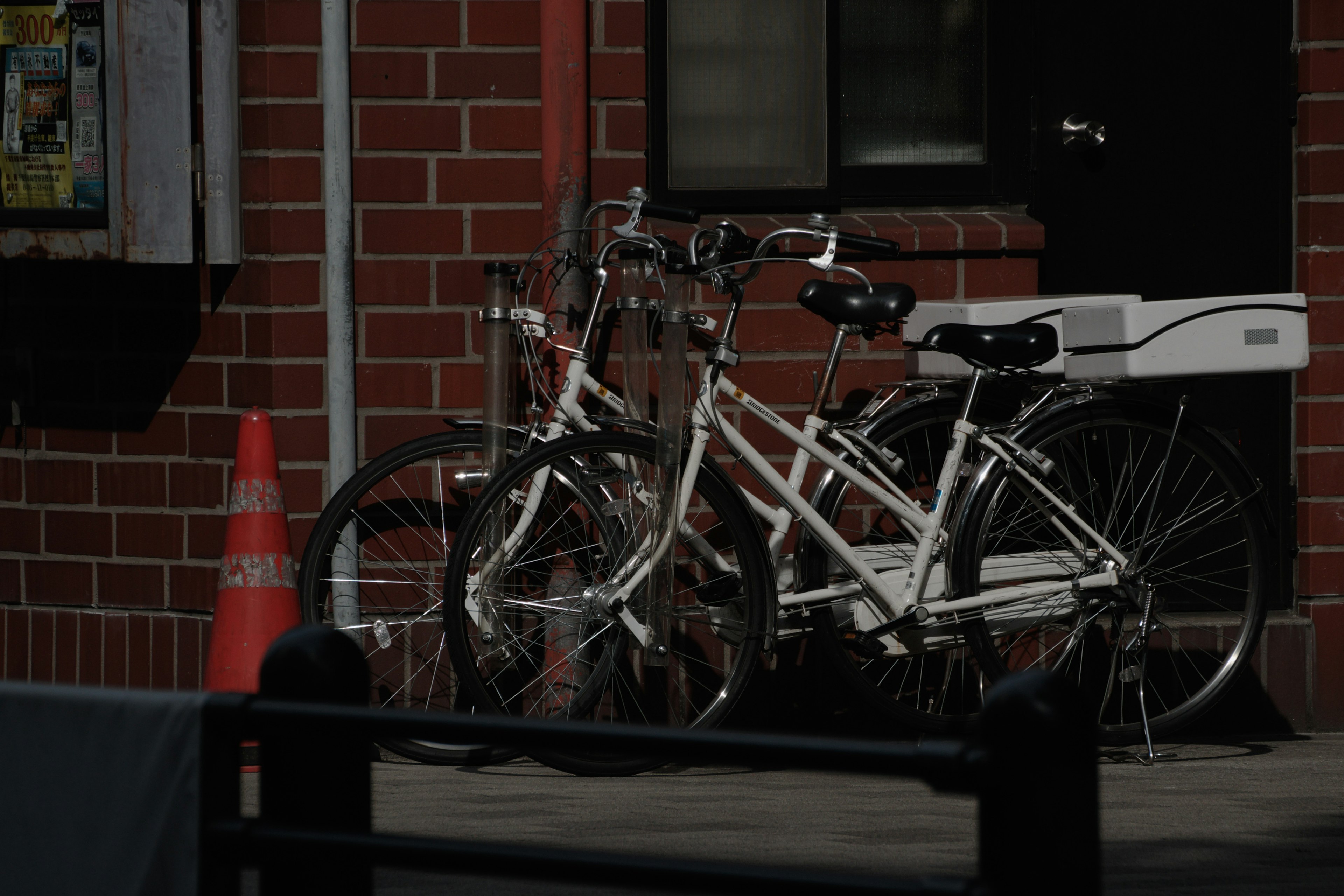 Group of white bicycles parked in front of a red brick wall