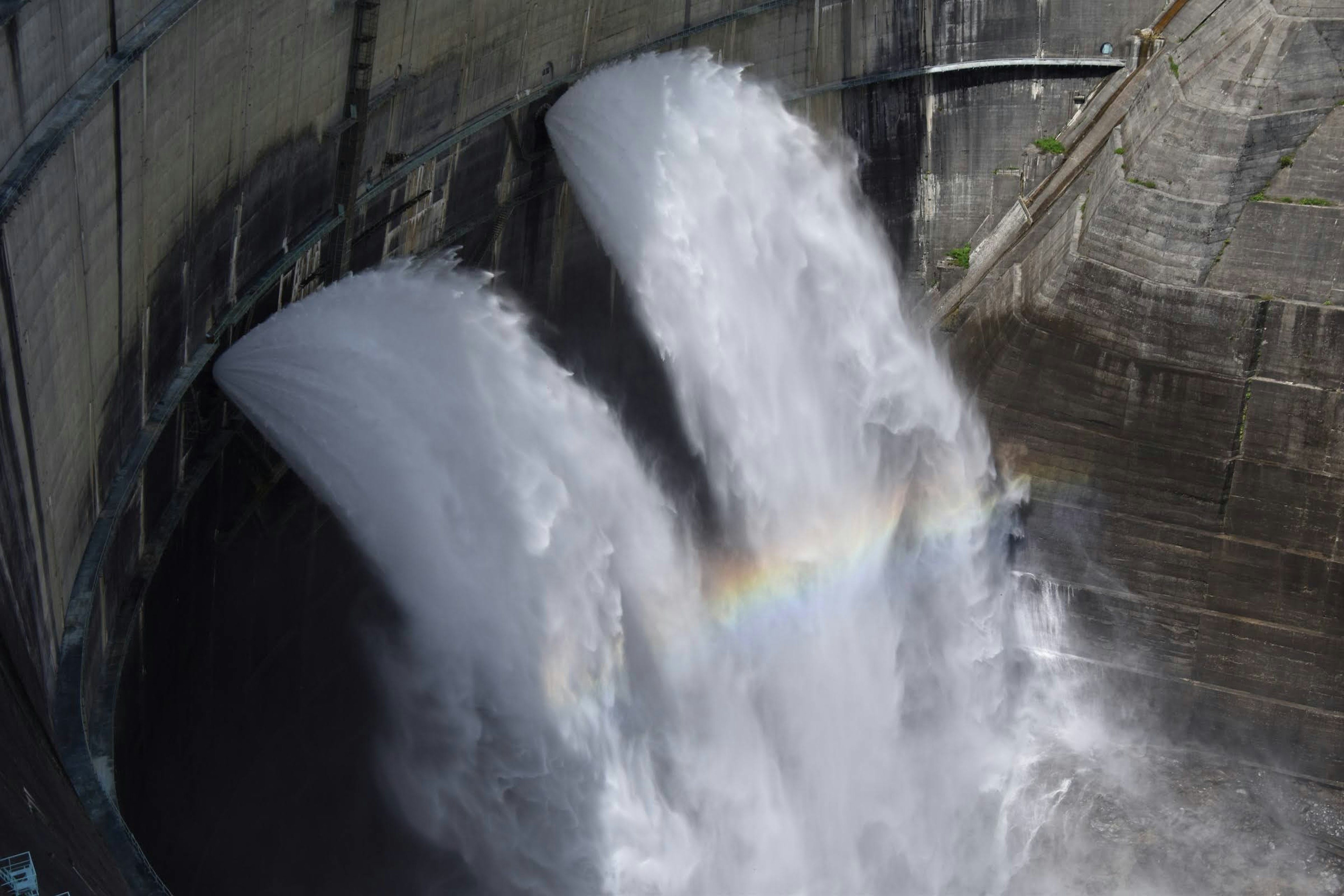 Wasser fließt aus einem Damm mit sichtbarem Regenbogen